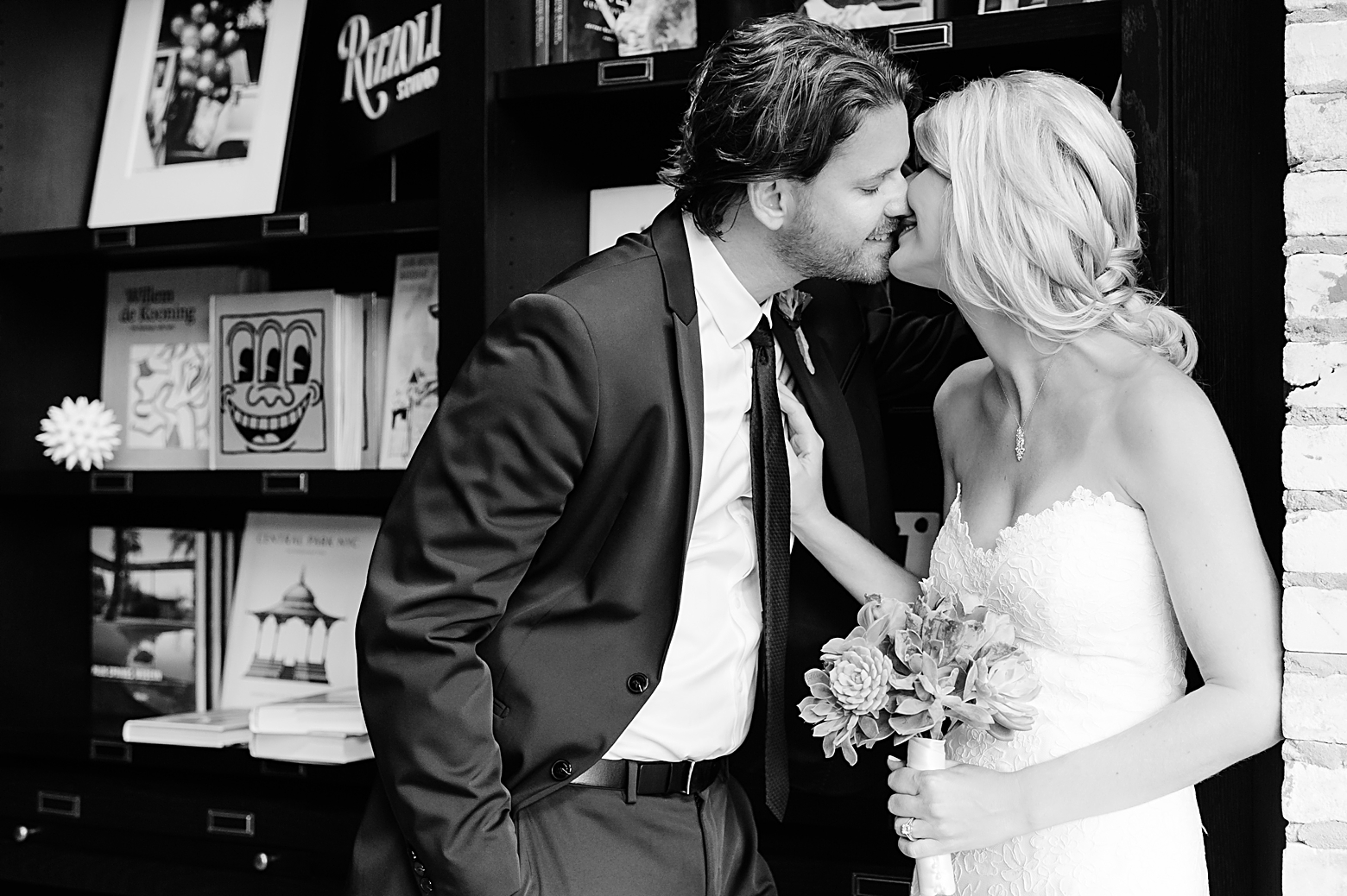 Bride and Groom sneak in some kisses near the books in the library of Oxford Exchange after their wedding day