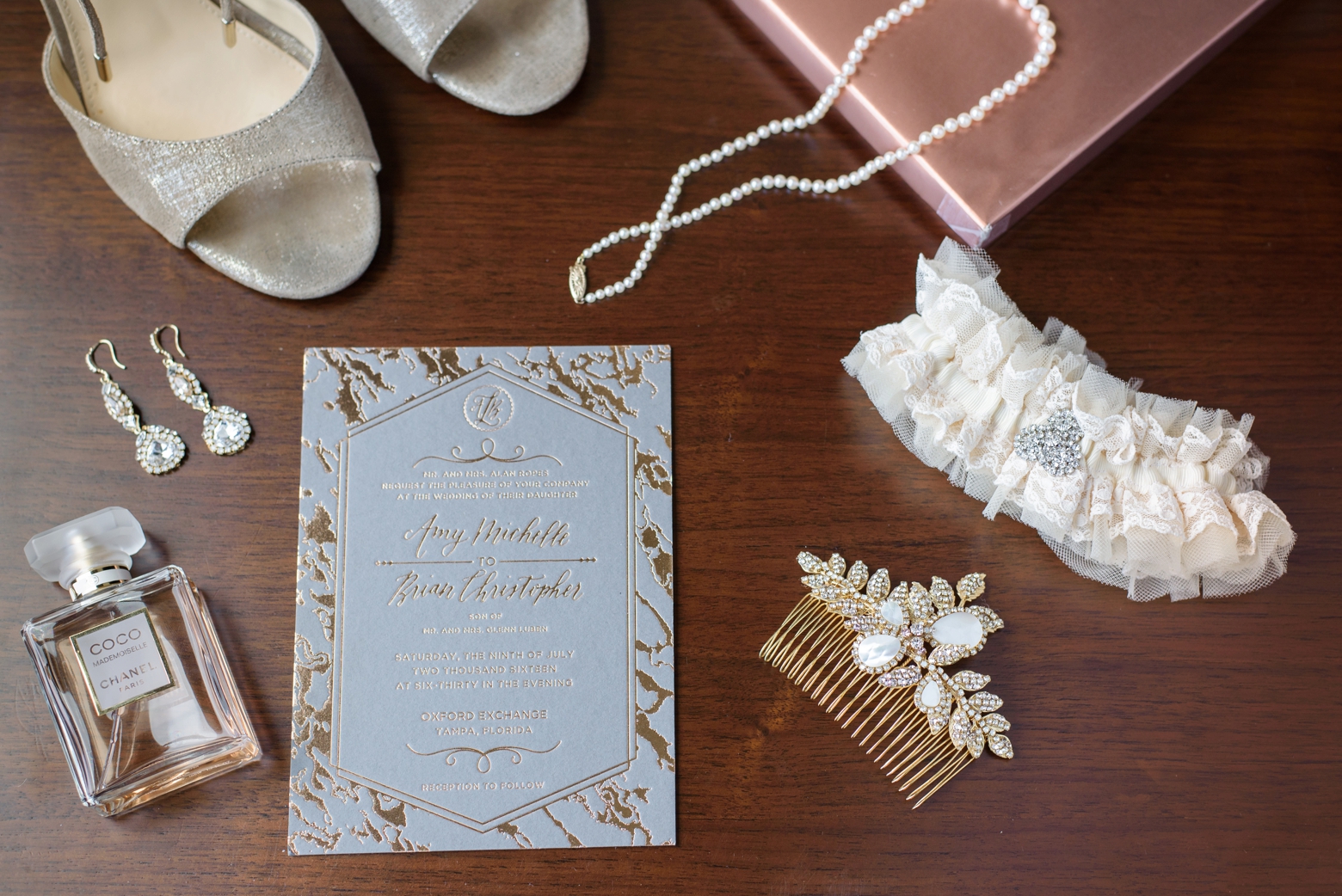 The Bridal details surrounding the wedding invitations on a wooden table