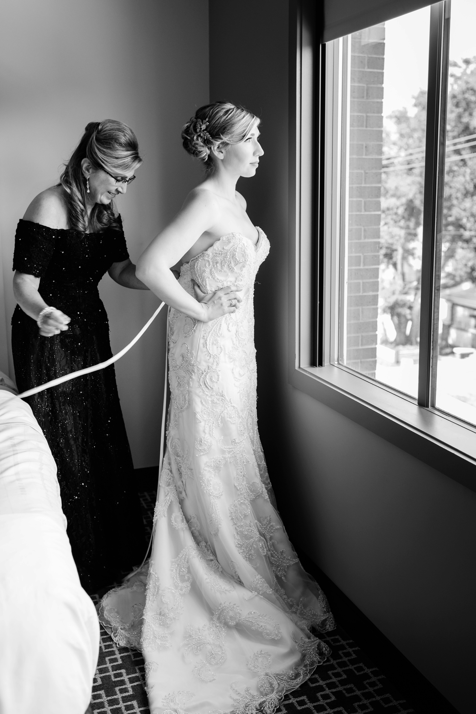 Bride and her Mom getting her into her wedding dress in timeless black and white