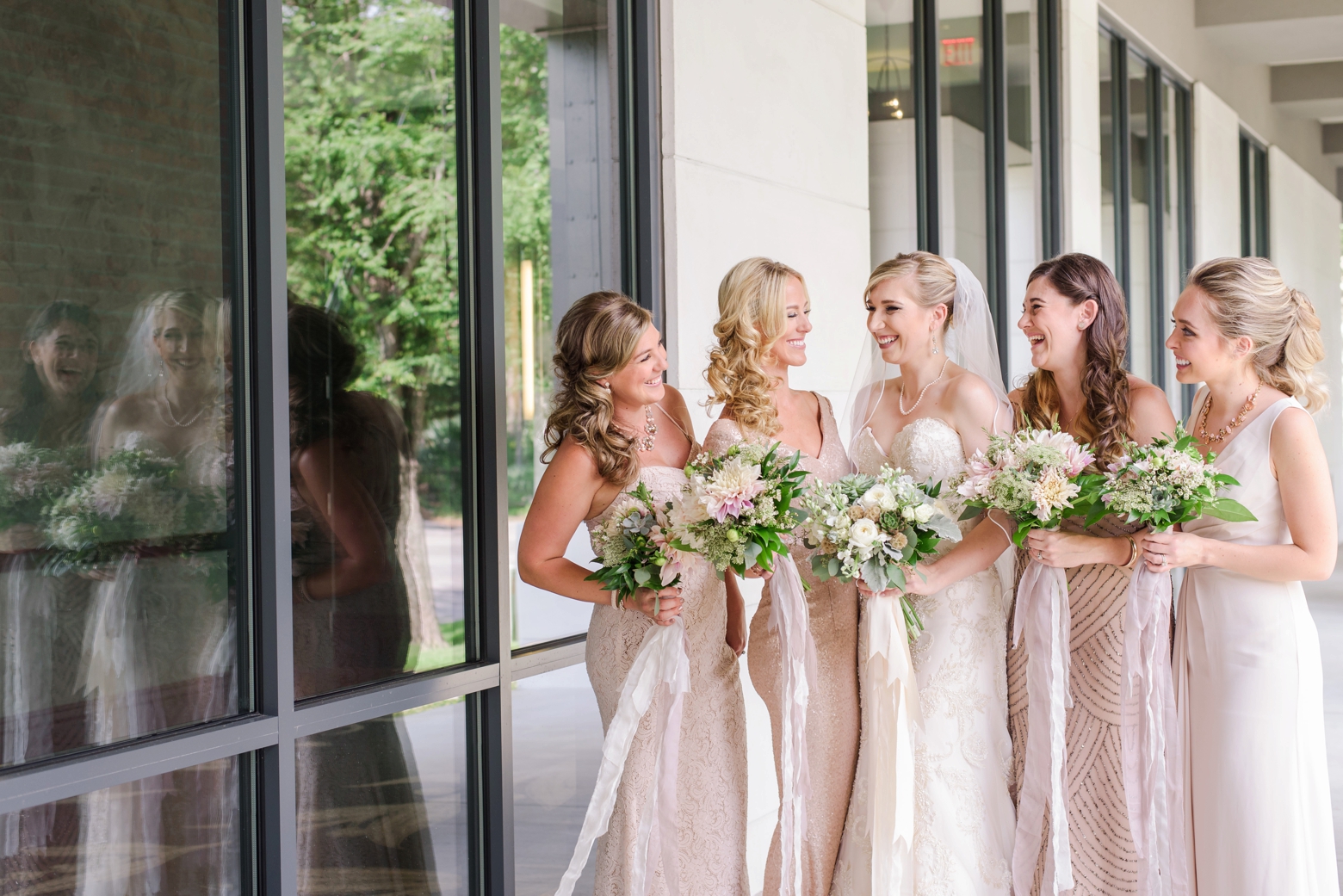 The Bride and her Bridesmaids holding their floral bouquet and laughing