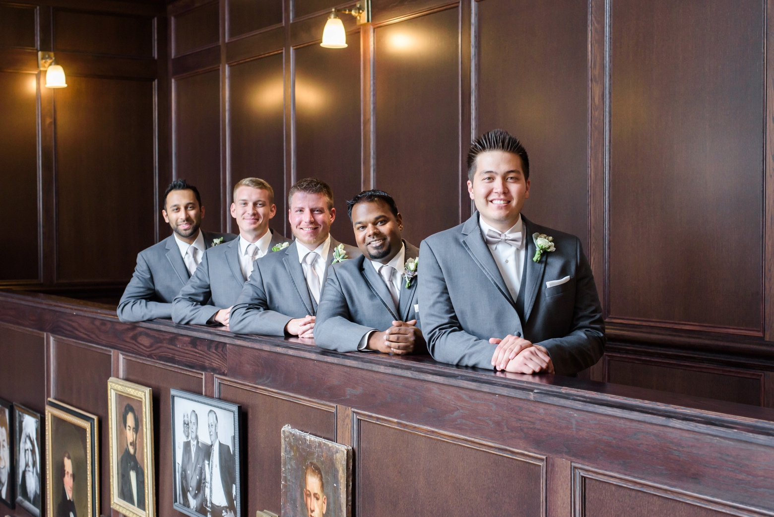 The Groom and Groomsmen pose along a wall in the atrium of Oxford Exchange