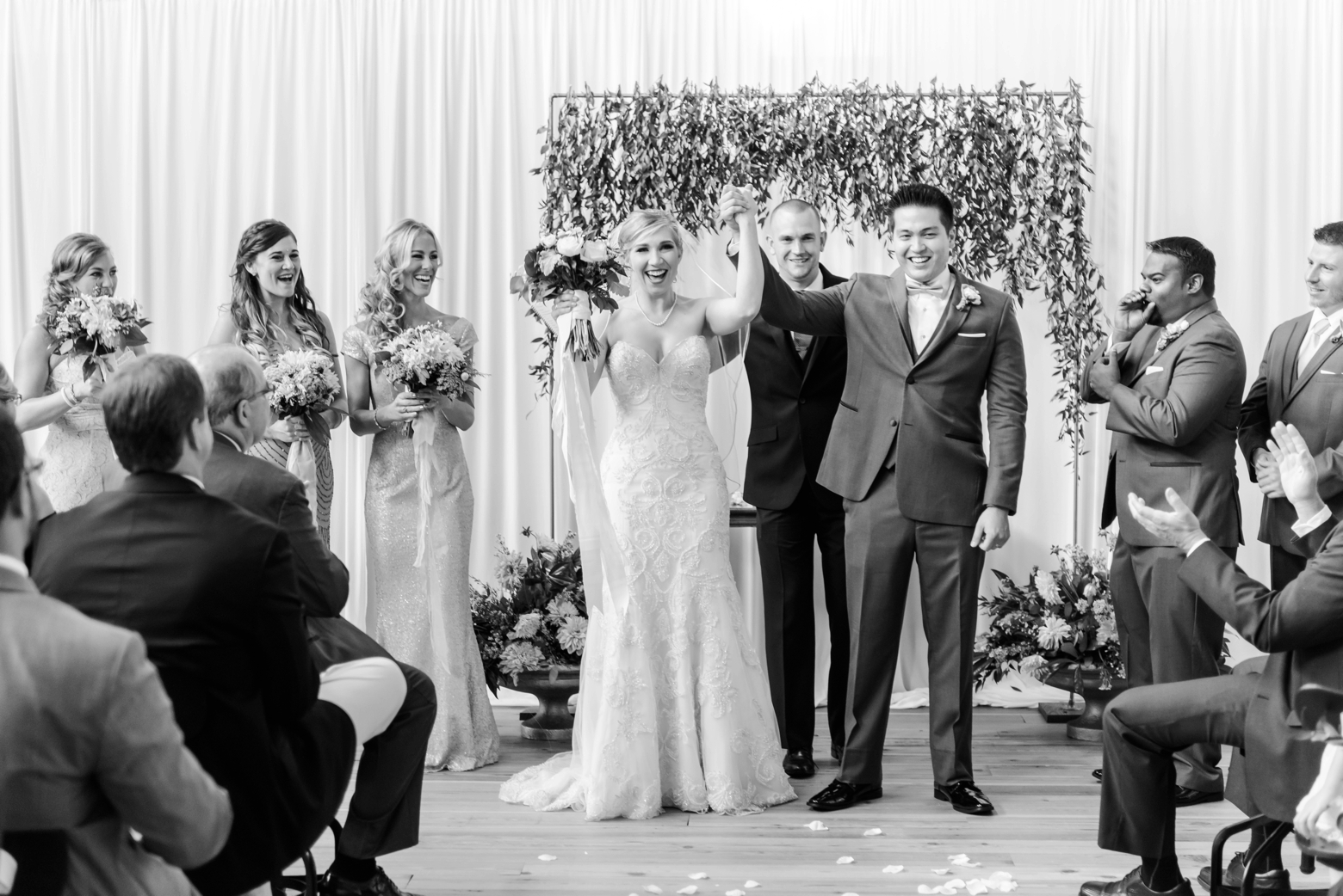 The Bride and Groom raise their arms after they say I do as their friends and family applaud