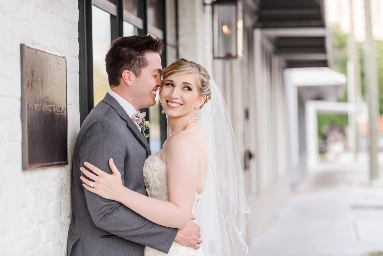 Beautiful portrait of the Bride and Groom along the white brick walls of the exterior of Oxford Exchange