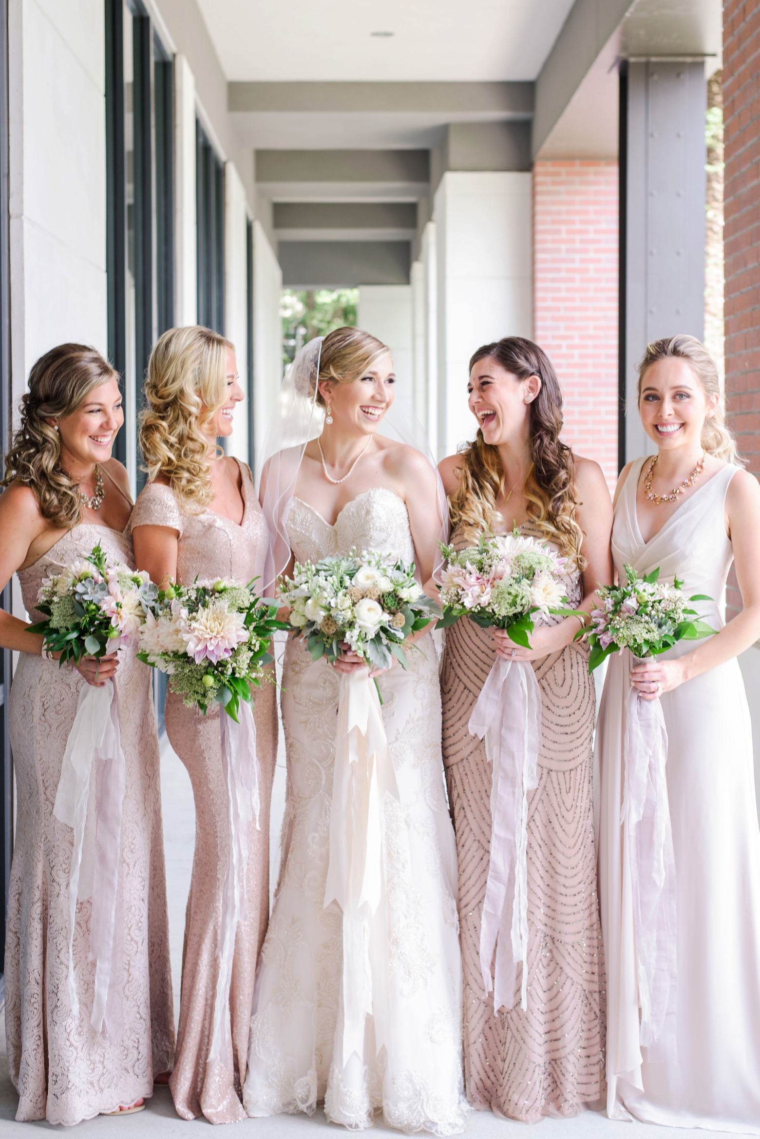 The Bride and her Bridesmaids bathed in sunshine holding their floral bouquets