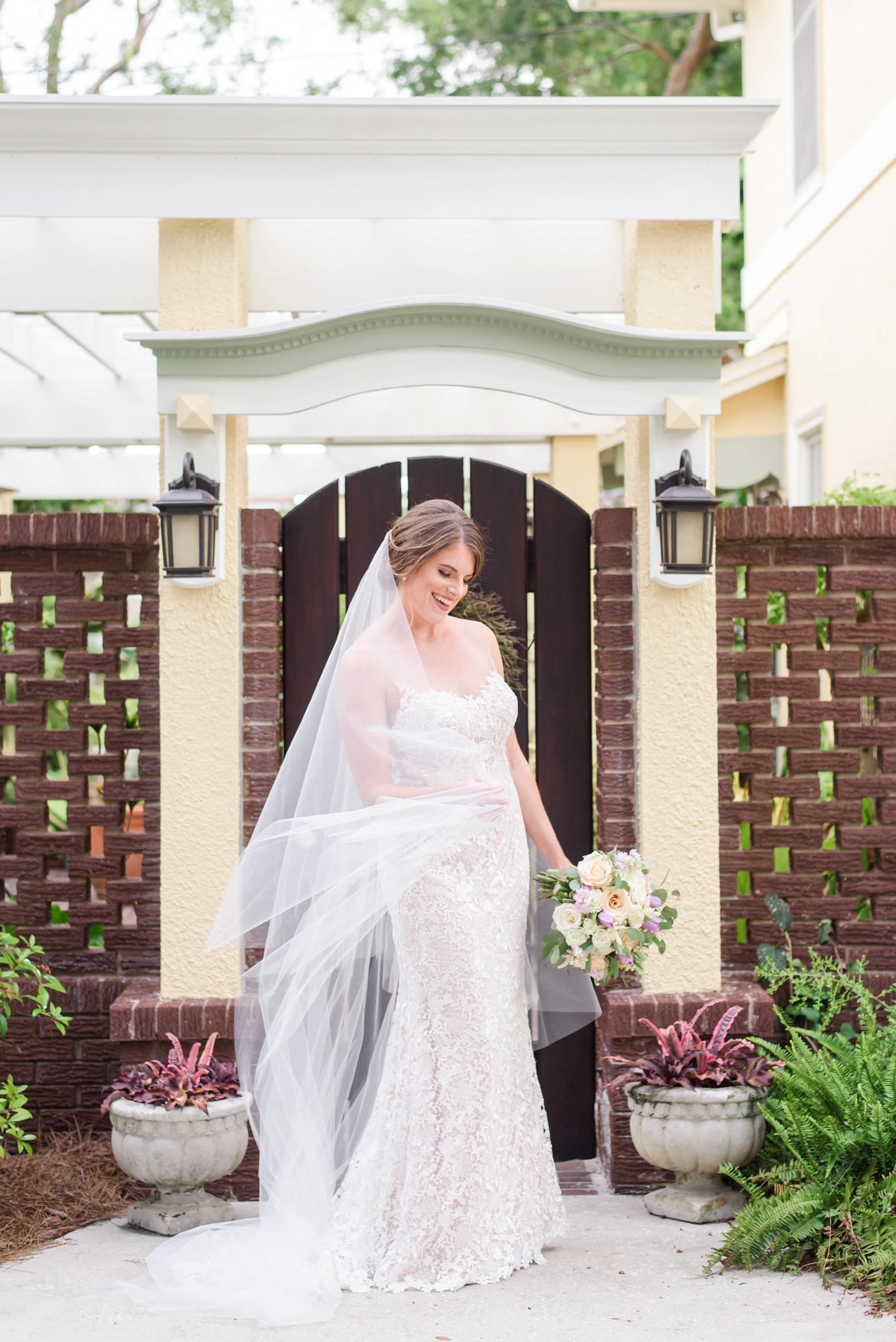 Bride twirls her wedding gown and veil in front of a gate