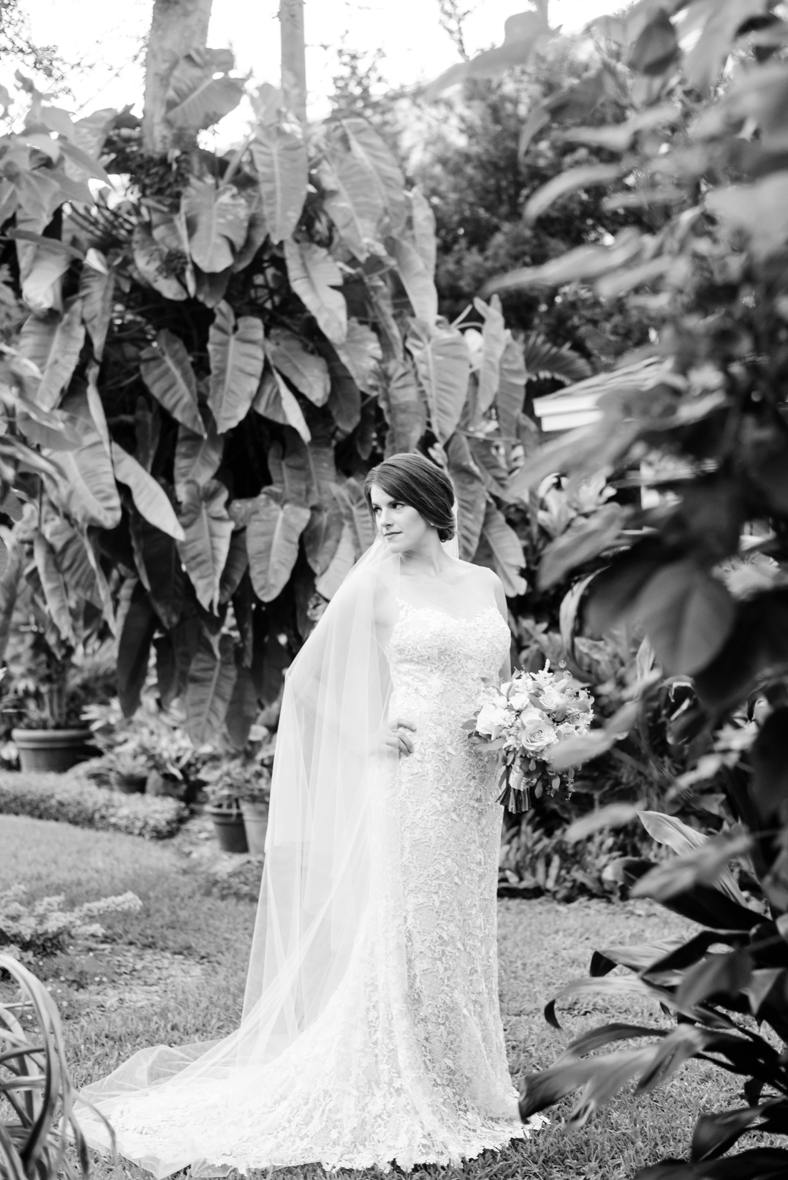 Black and white photo of a bride looking over her shoulder in the yard of her childhood home in Tampa
