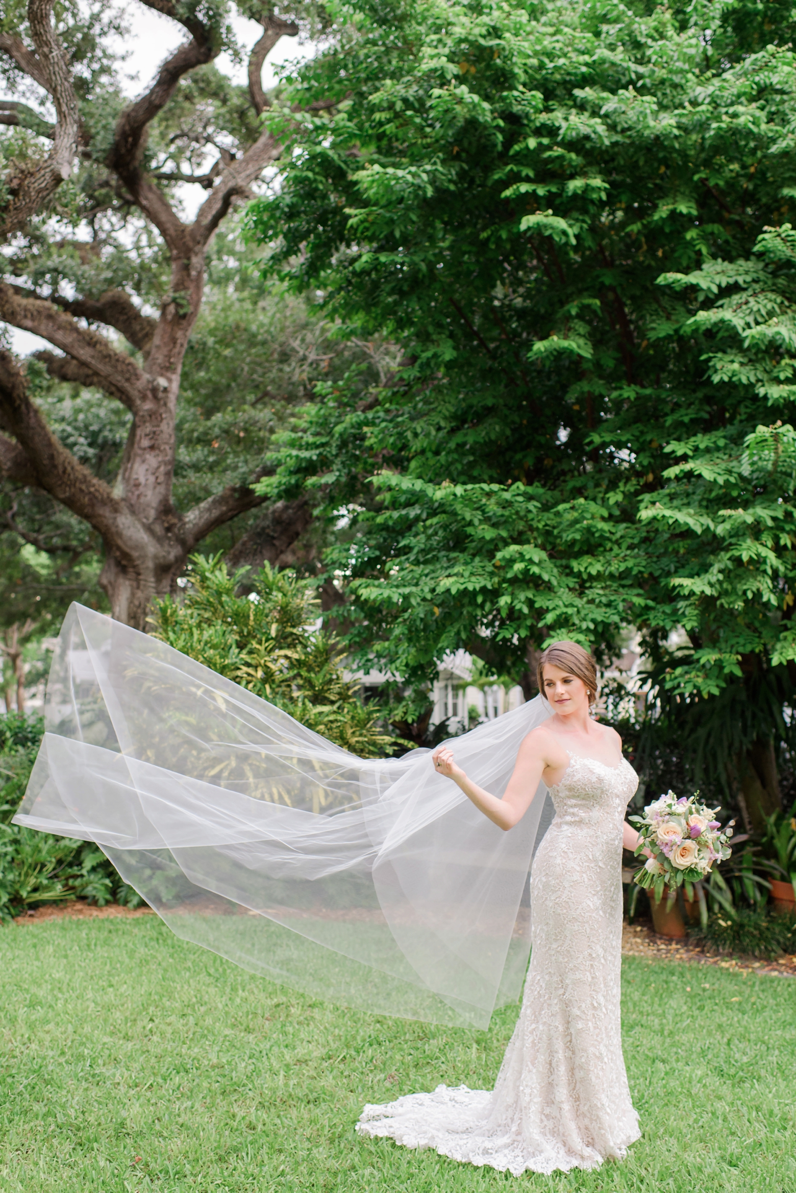 Bride holds her veil while it blows in the wind 