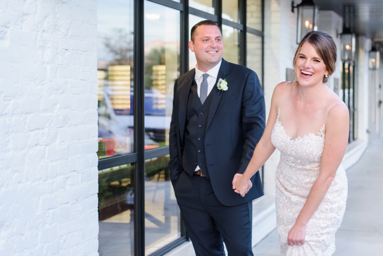 A bride laughs while holding her grooms hand outside the oxford exchange wedding reception venue