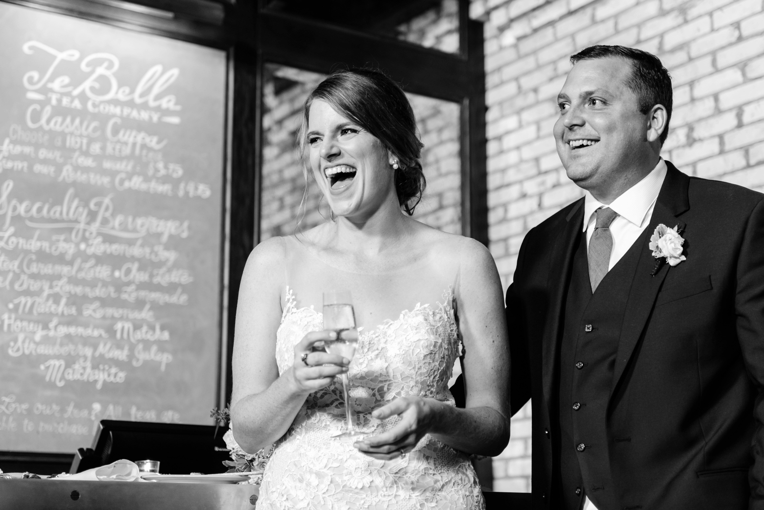 Black and white image of a Bride laughing next to her Groom in the atrium of their oxford exchange wedding reception