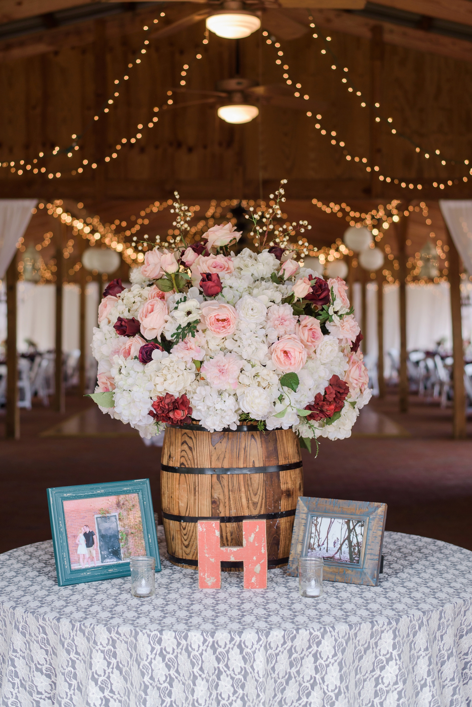 The welcome table at the entrance of the barn with a large floral arrangement and candles