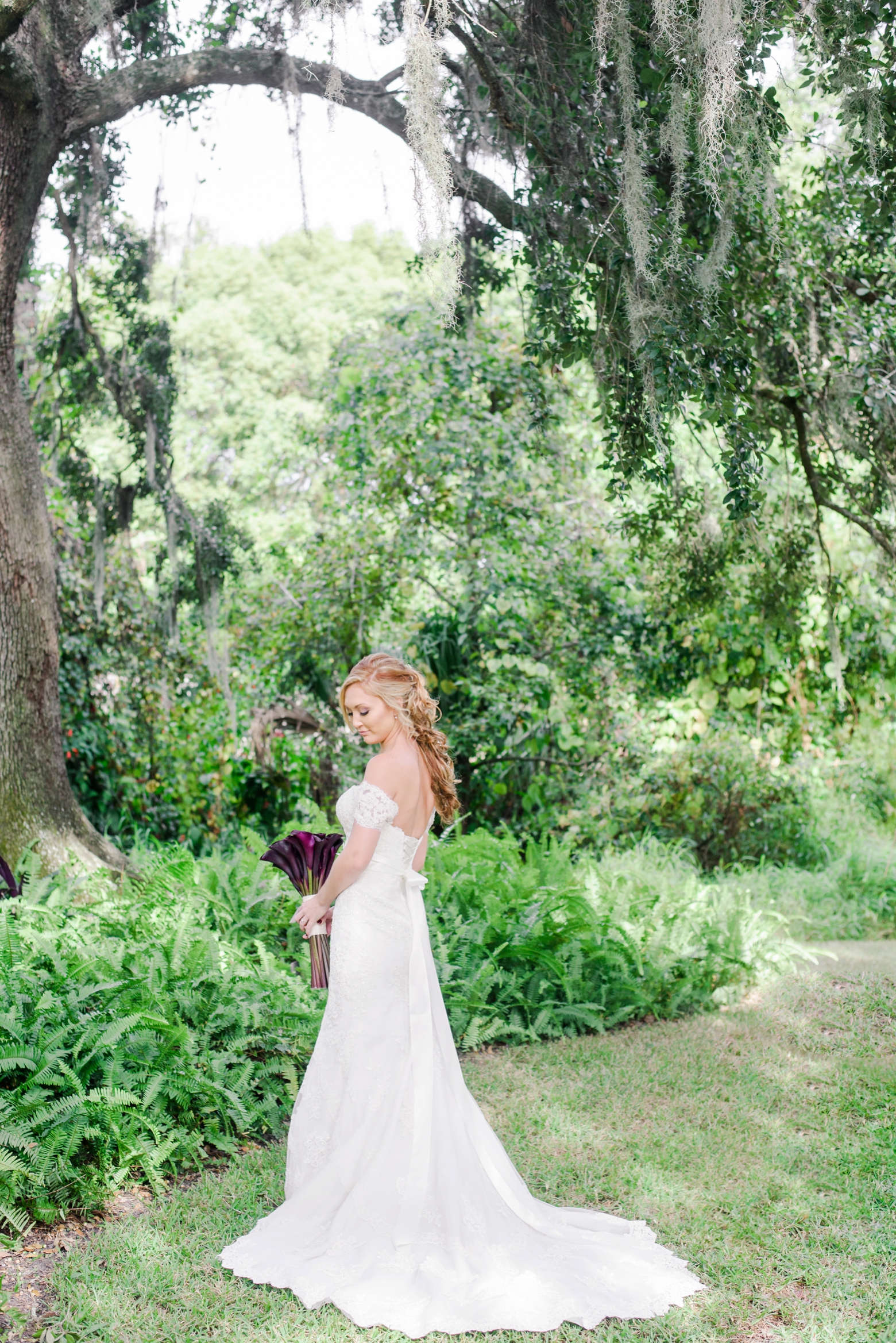 Formal portrait of the Bride holding her floral bouquet under some old Oak trees