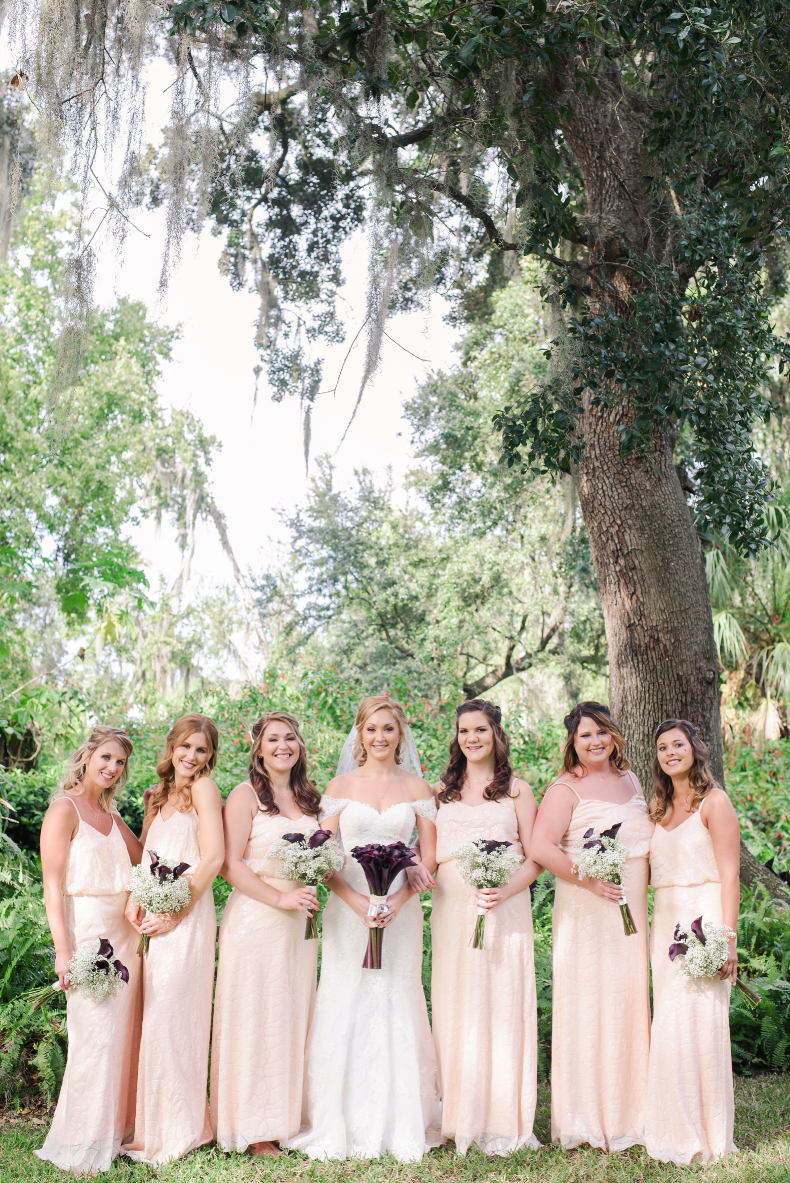 The Bride and her Bridesmaids pose holding their own floral bouquets