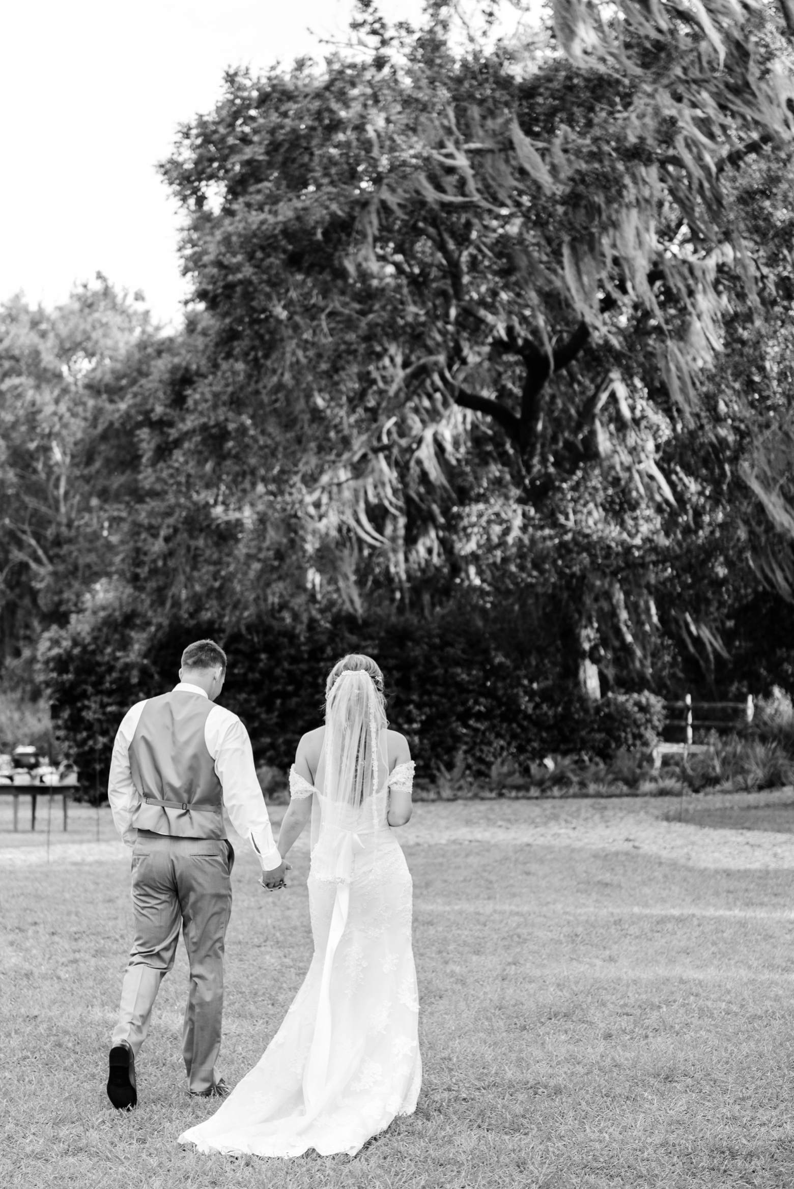 Bride and Groom walk towards their wedding reception after saying their I do's under the oak tree at Cross Creek Ranch
