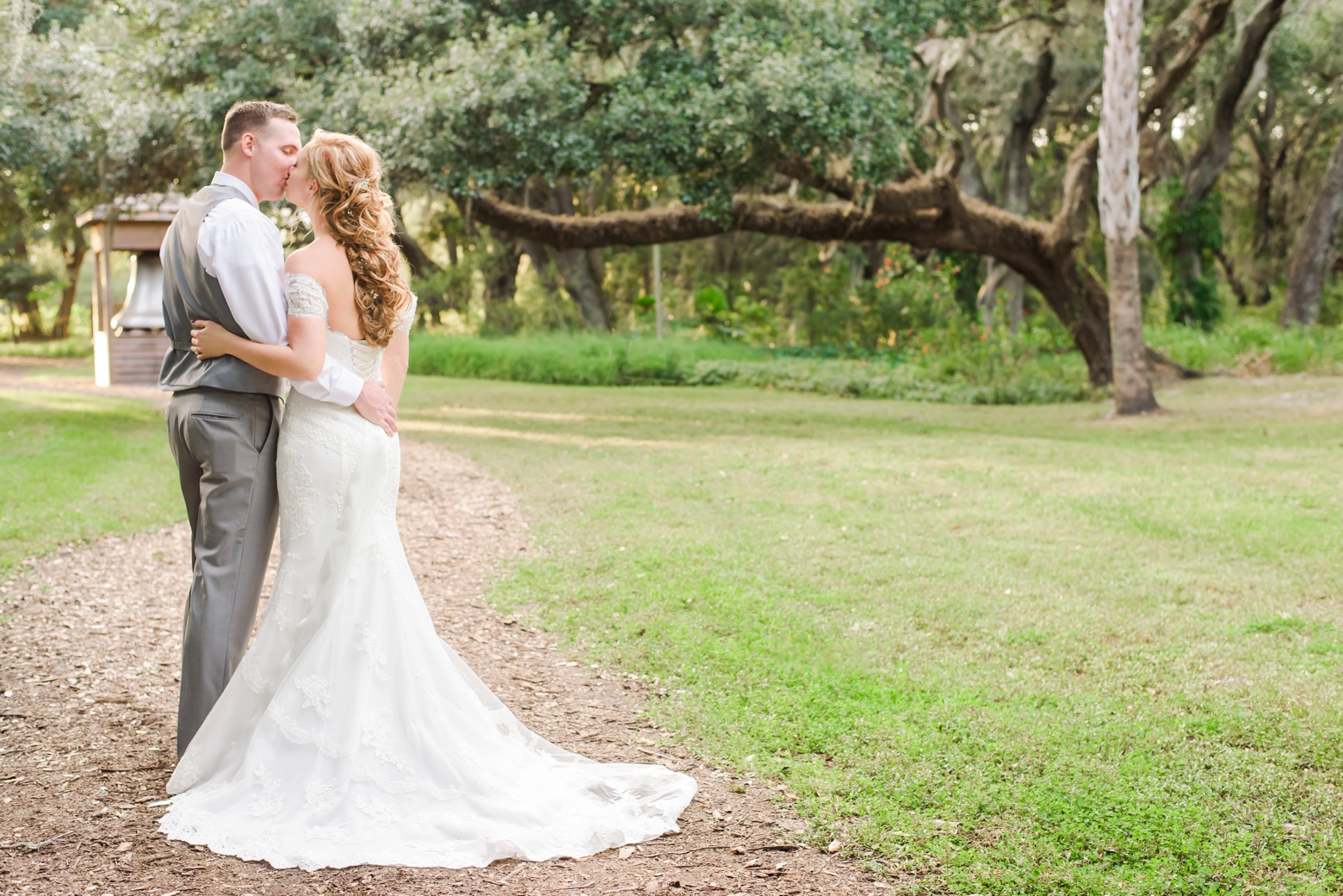 Bride and groom share a kiss on a path to their reception after their Cross Creek Ranch Wedding ceremony