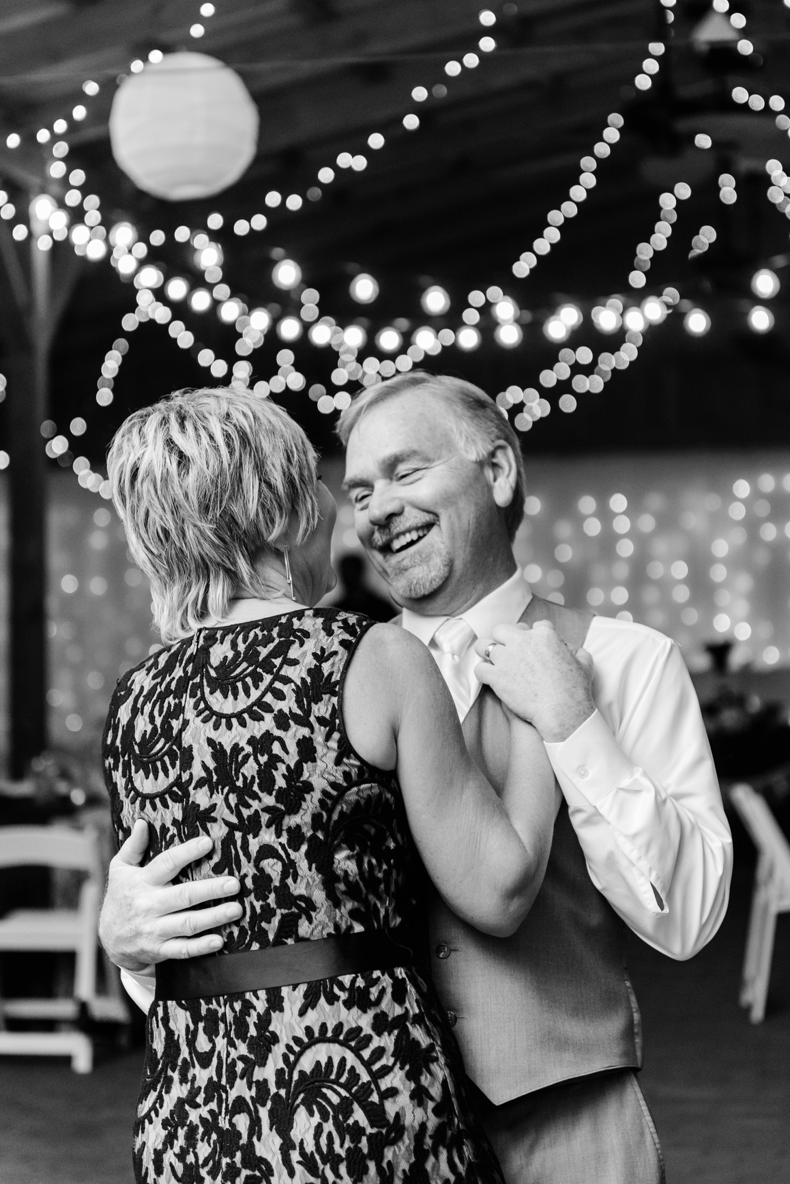Father of the Bride and his wife dance under the lights during a Cross Creek Ranch wedding day