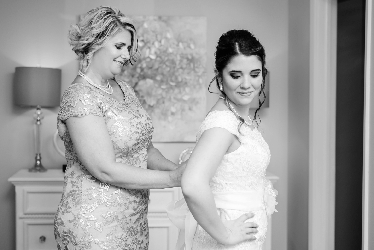 Bride with her Mom helping her into her wedding dress by Sarah and Ben Photography