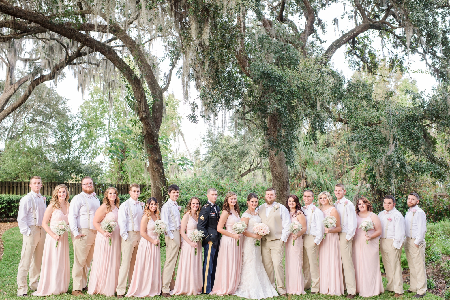 The Wedding party pose for a formal photo under the ancient oaks of Cross Creek Ranch  by Sarah and Ben Photography