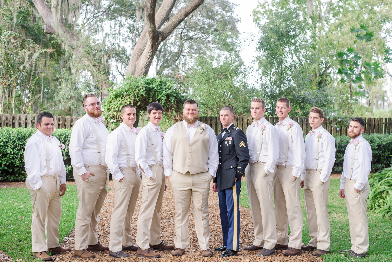 Groom and his Groomsmen pose in a line under the oak trees