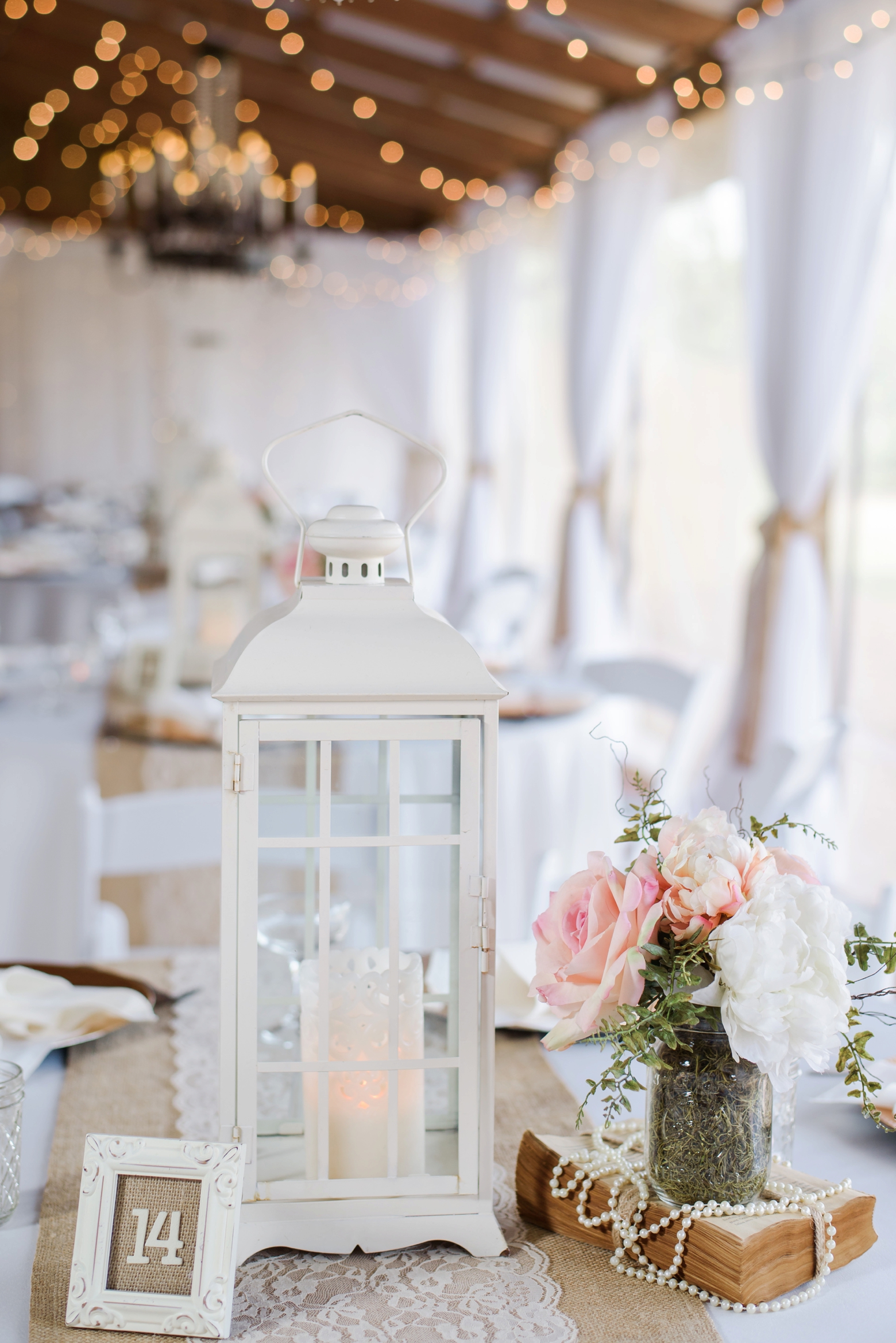 Table numbers and centerpieces filled with old books and pink and white roses
