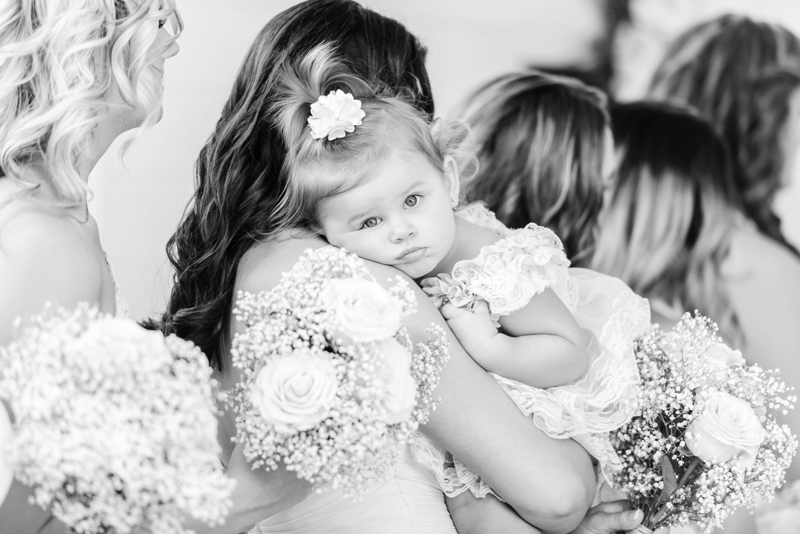Bridesmaid hold the flower girl in timeless black and white photography