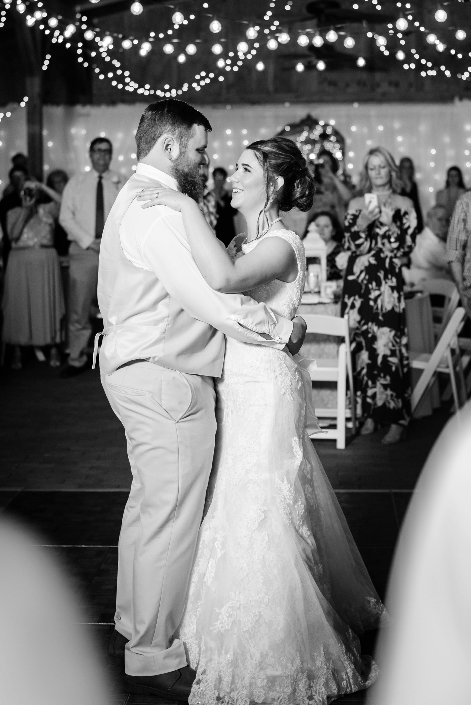 Bride and Groom share a first dance under the twinkle lights of the Cross Creek Ranch barn