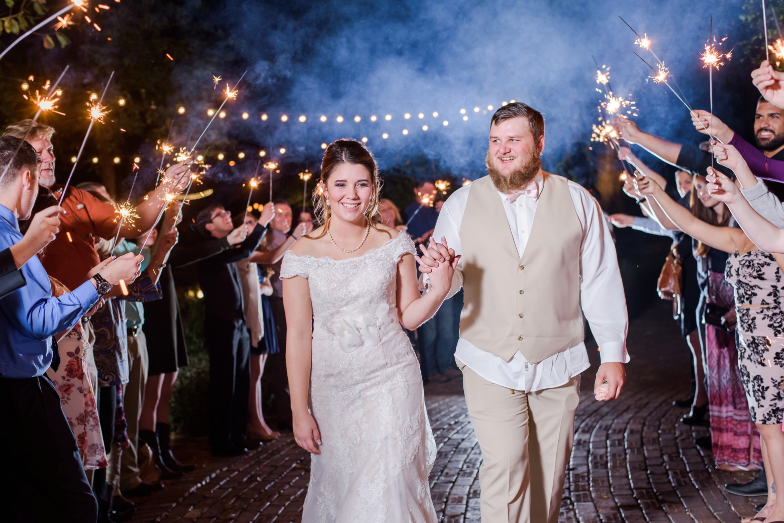 Bride and Groom exit their cross creek wedding reception under the sparklers held by their family and friends