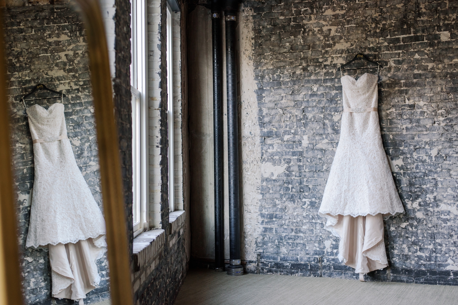 A wedding gown hangs on a brick wall before an Oxford exchange wedding ceremony