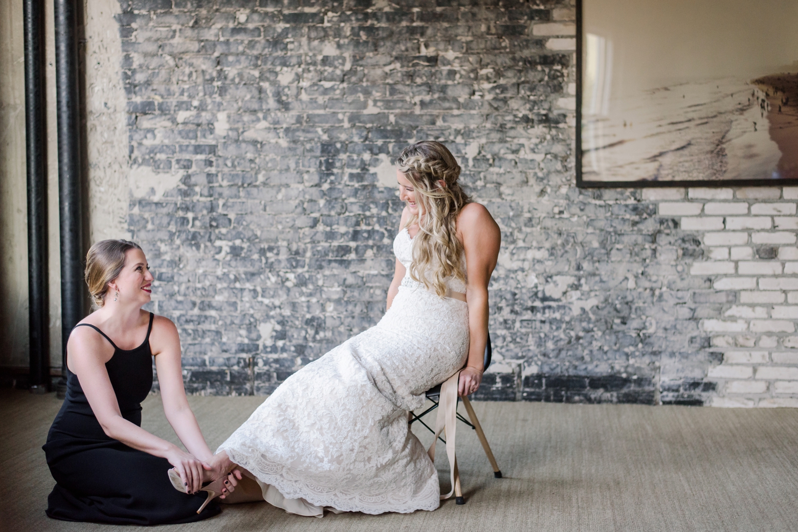 Bride being assisted by her bridesmaid into her shoes in Tampa, FL