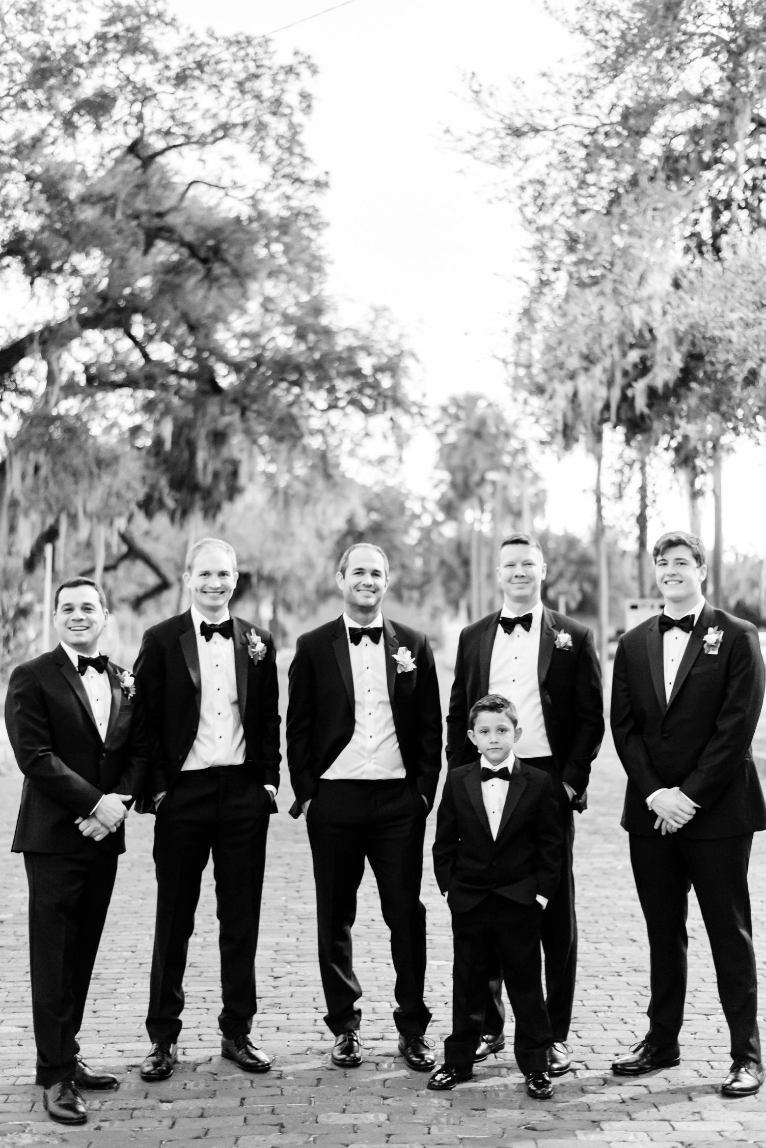 Groom and his Groomsmen in classic black and white pose for a formal photo in the street