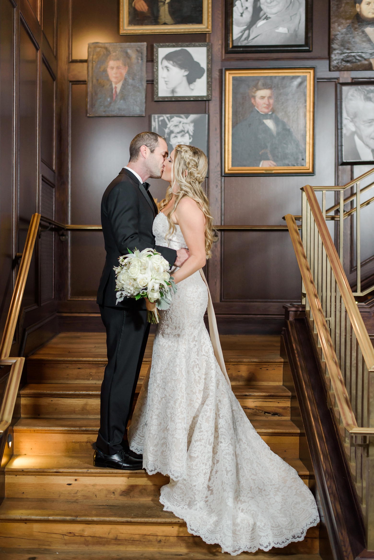 Bride and Groom kiss on a staircase as her dresses train cascades down the steps