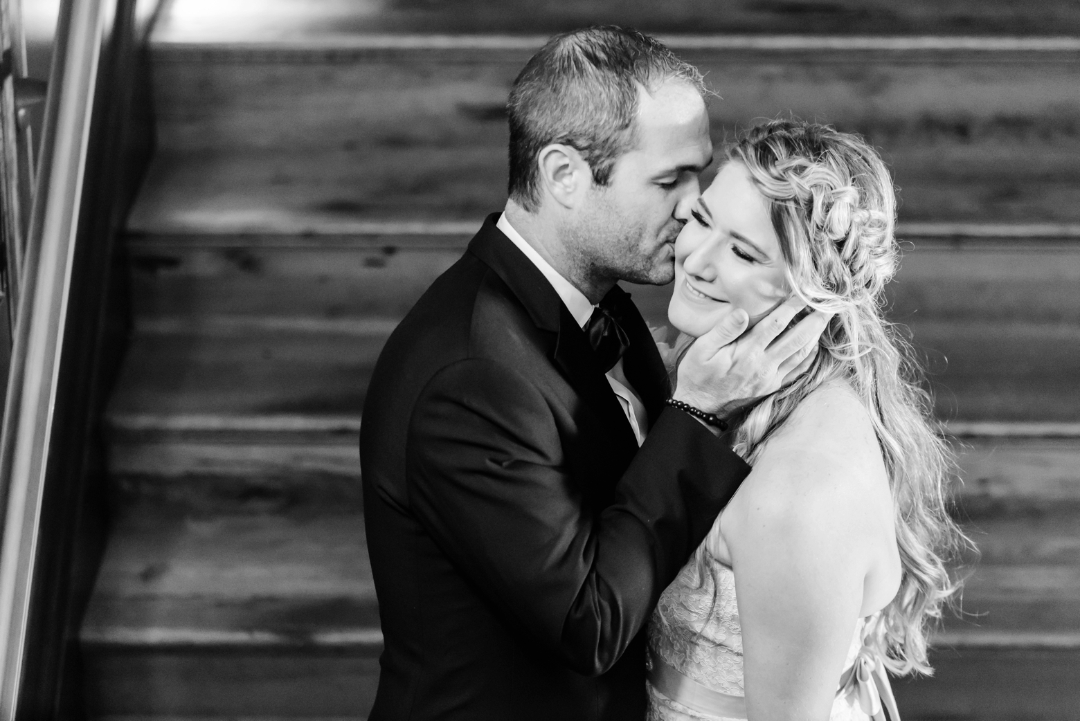 Groom kisses his Bride on the cheek in black and white