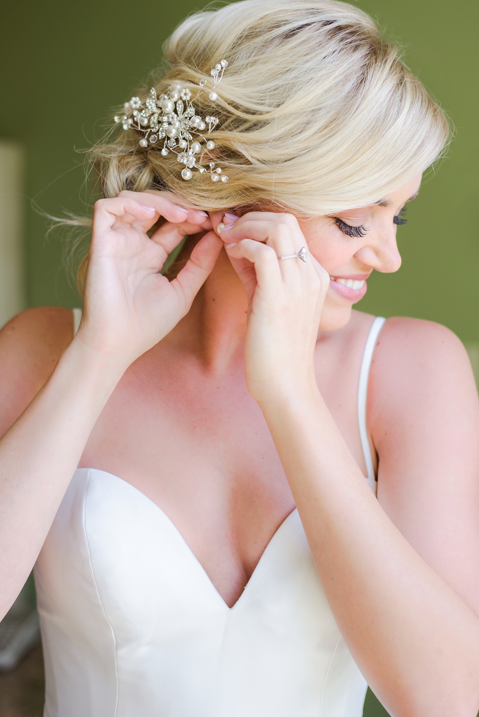 Beautiful bride inserting her pearl earrings by Sarah & Ben