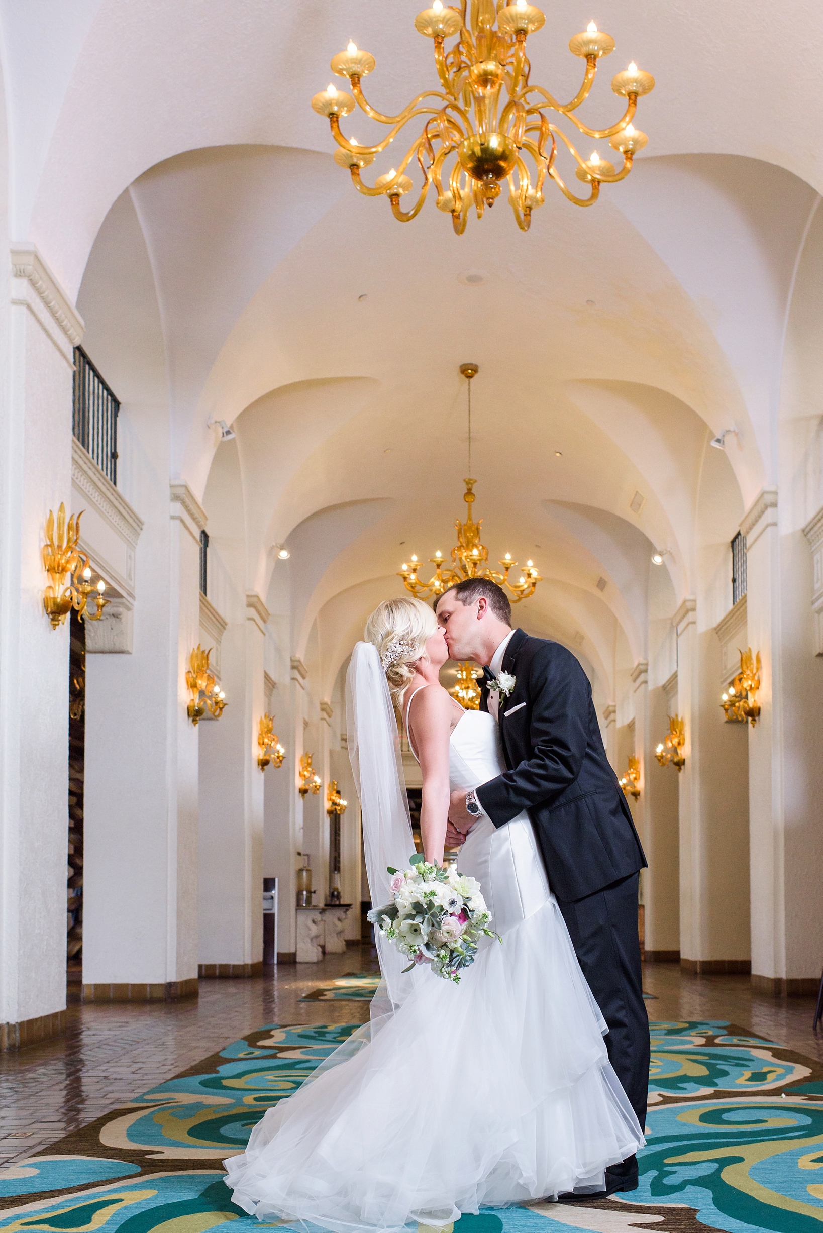 Bride and Groom share a kiss under the chandeliers by Sarah & Ben Photography