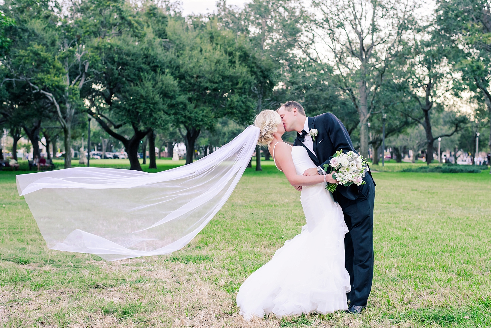 Bride and Groom in a deep kiss as the wind blows the veil