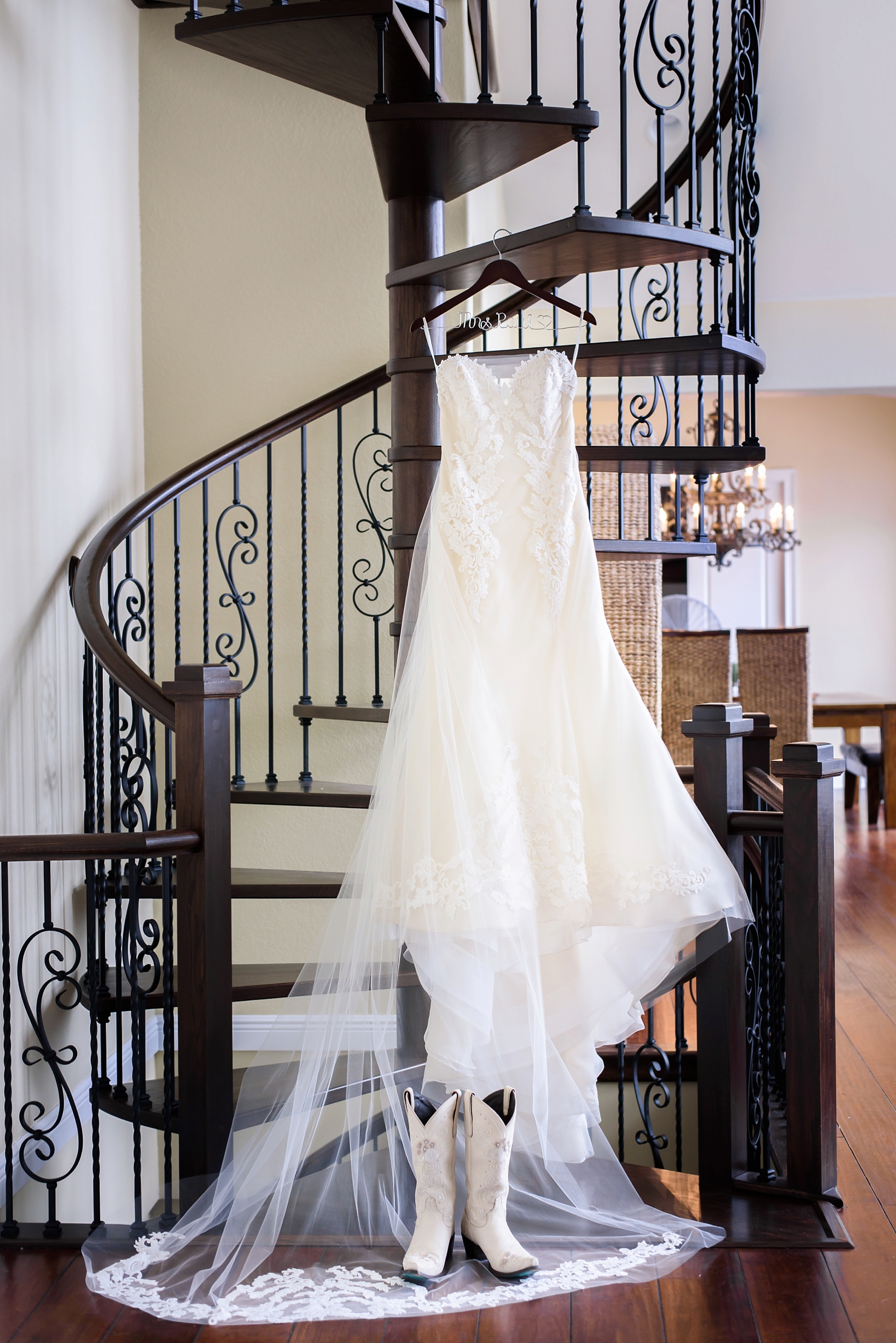 Wedding dress and boots hanging on metal spiral staircase by Sarah & Ben Photography