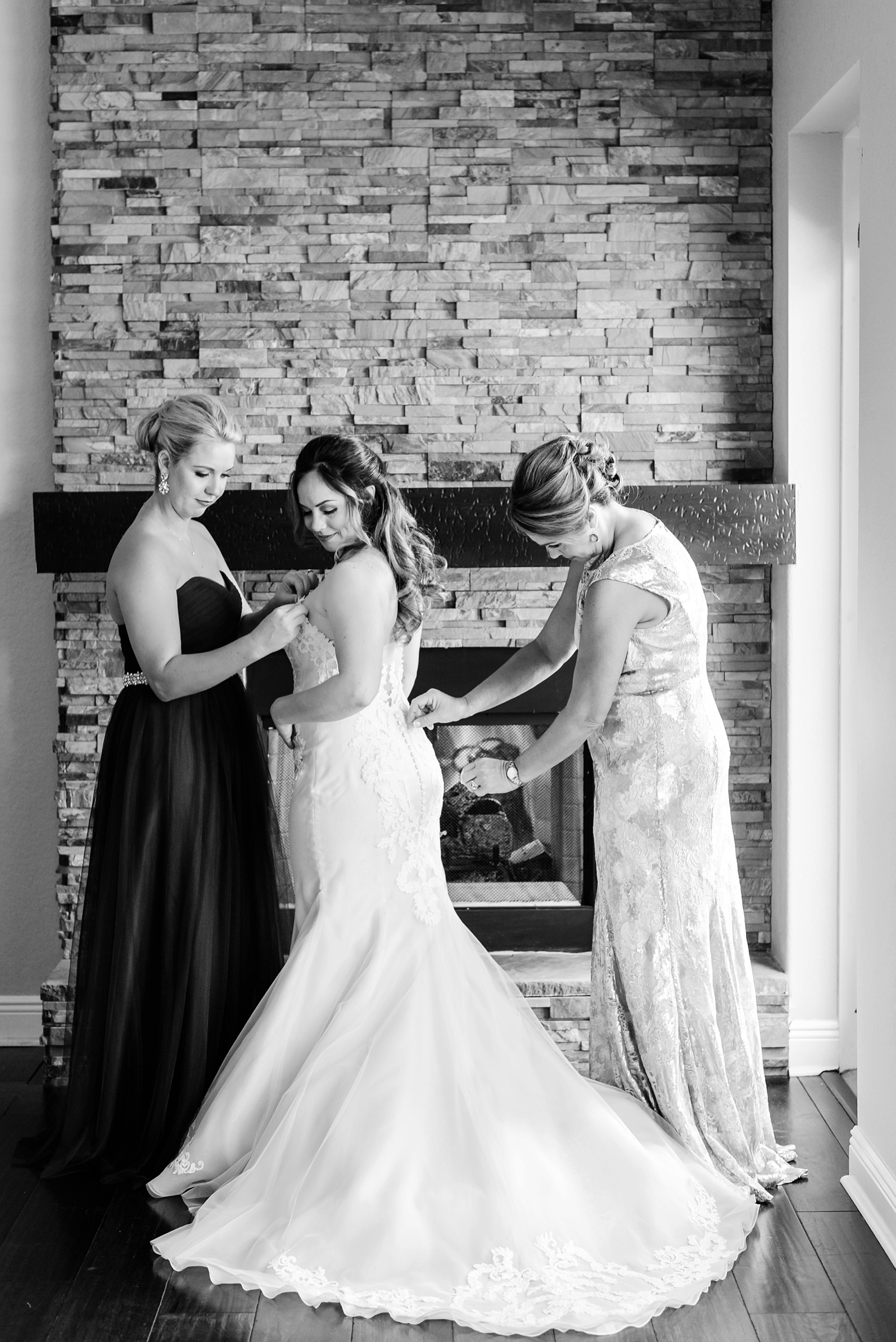 Black and white image of the bride getting into her wedding dress