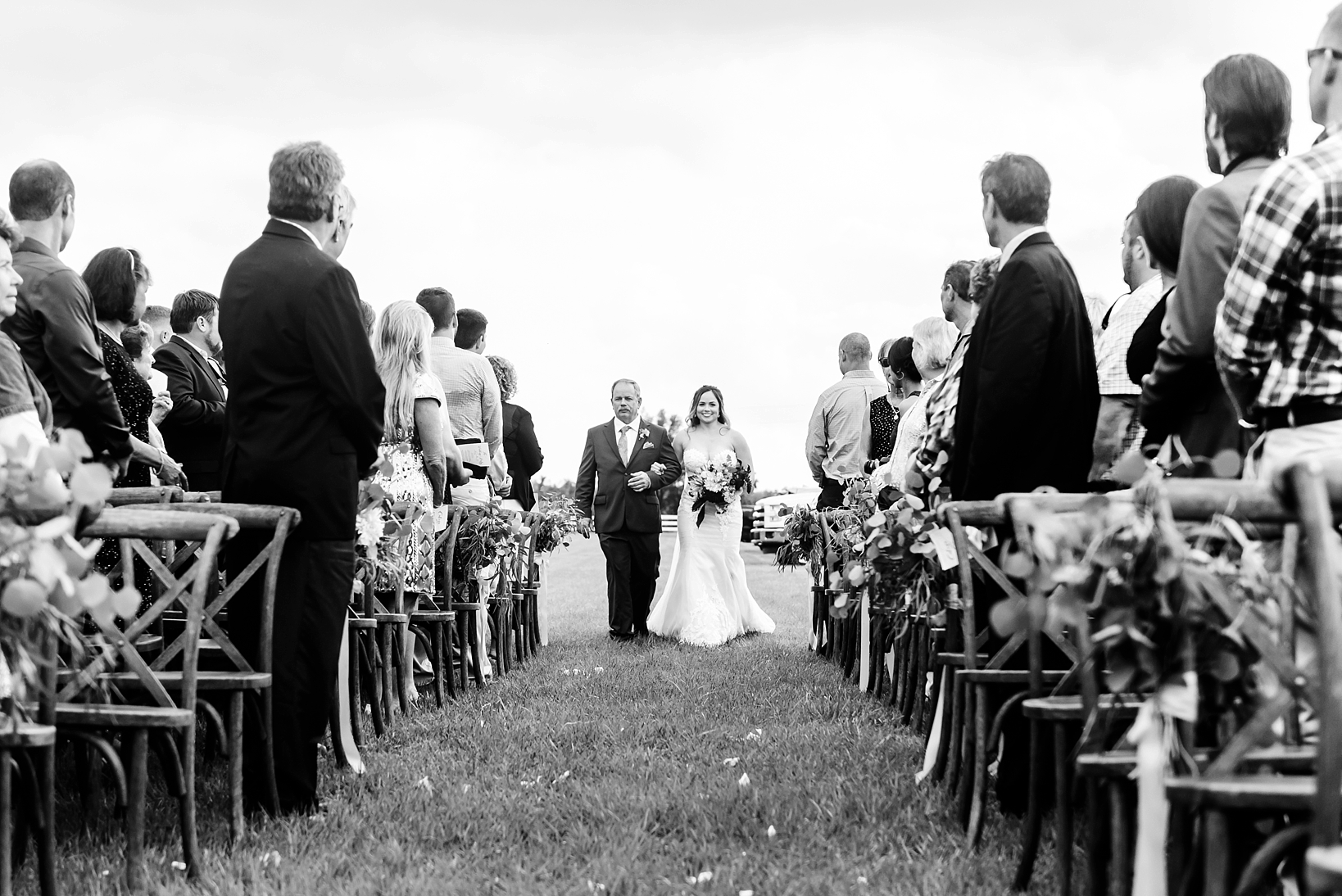 Bride and her father walking down the aisle while guests look on
