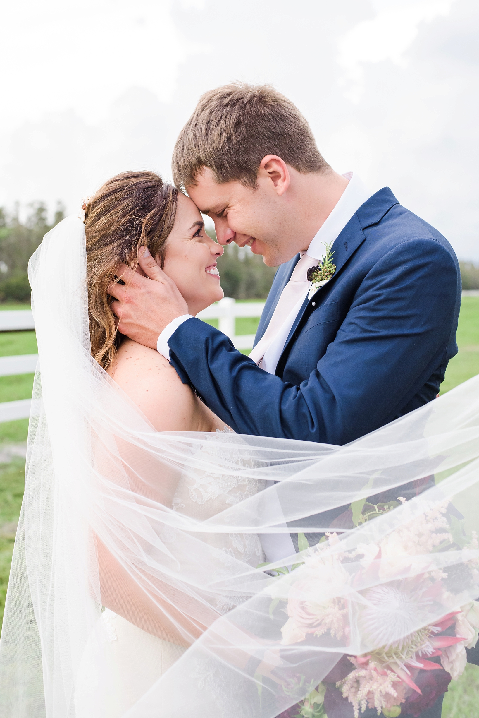 Bride and Groom sharing a private moment as the wind wraps the veil around the couple by Sarah & Ben Photography