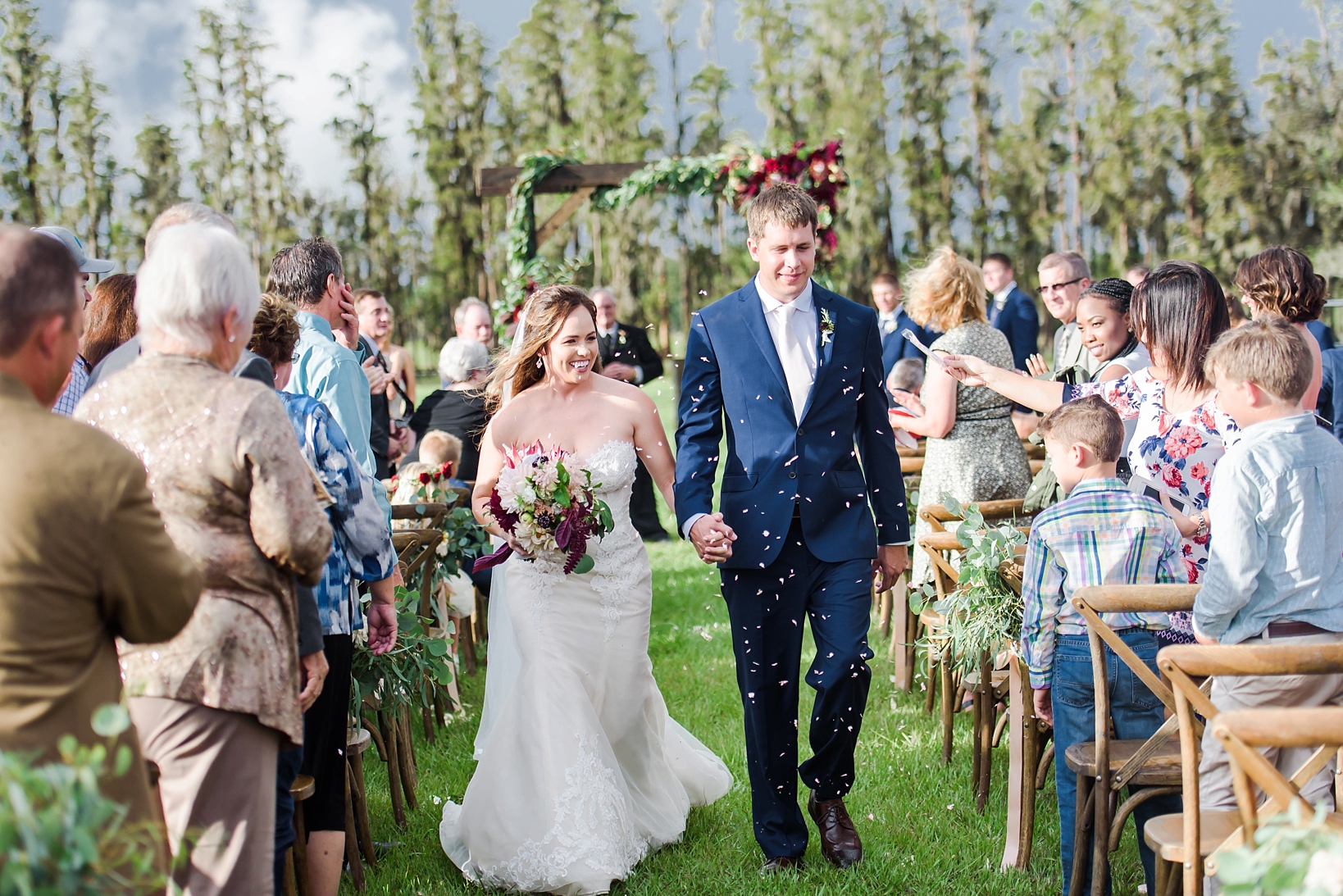 Rose petals are thrown at the couple as they proceed up the aisle