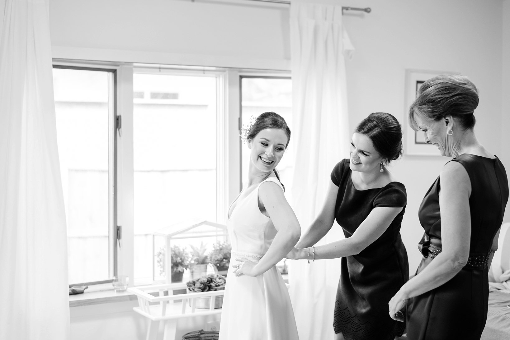 black and white image of the bride getting into her dress