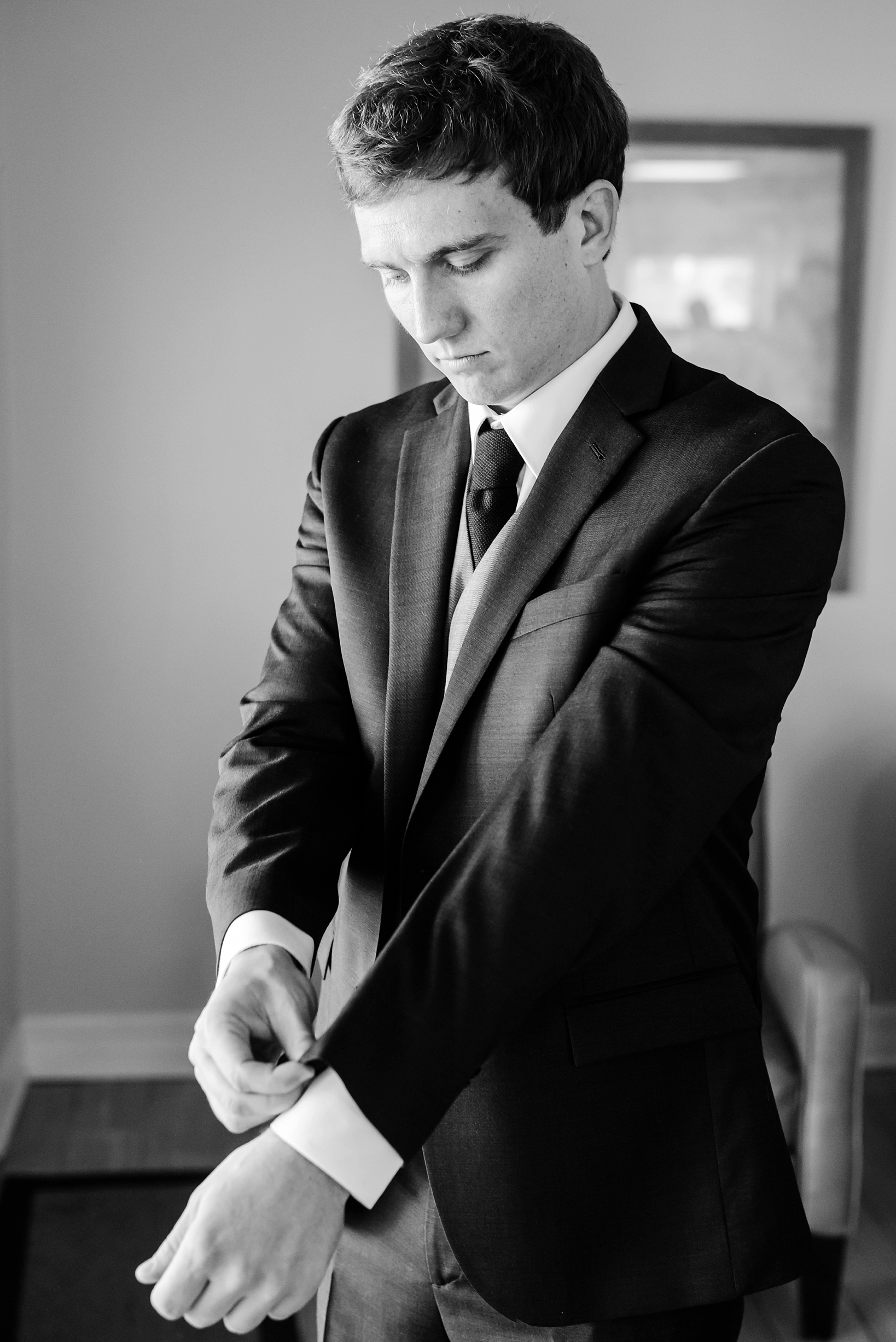 Groom in black and white getting his suit jacket on for his wedding