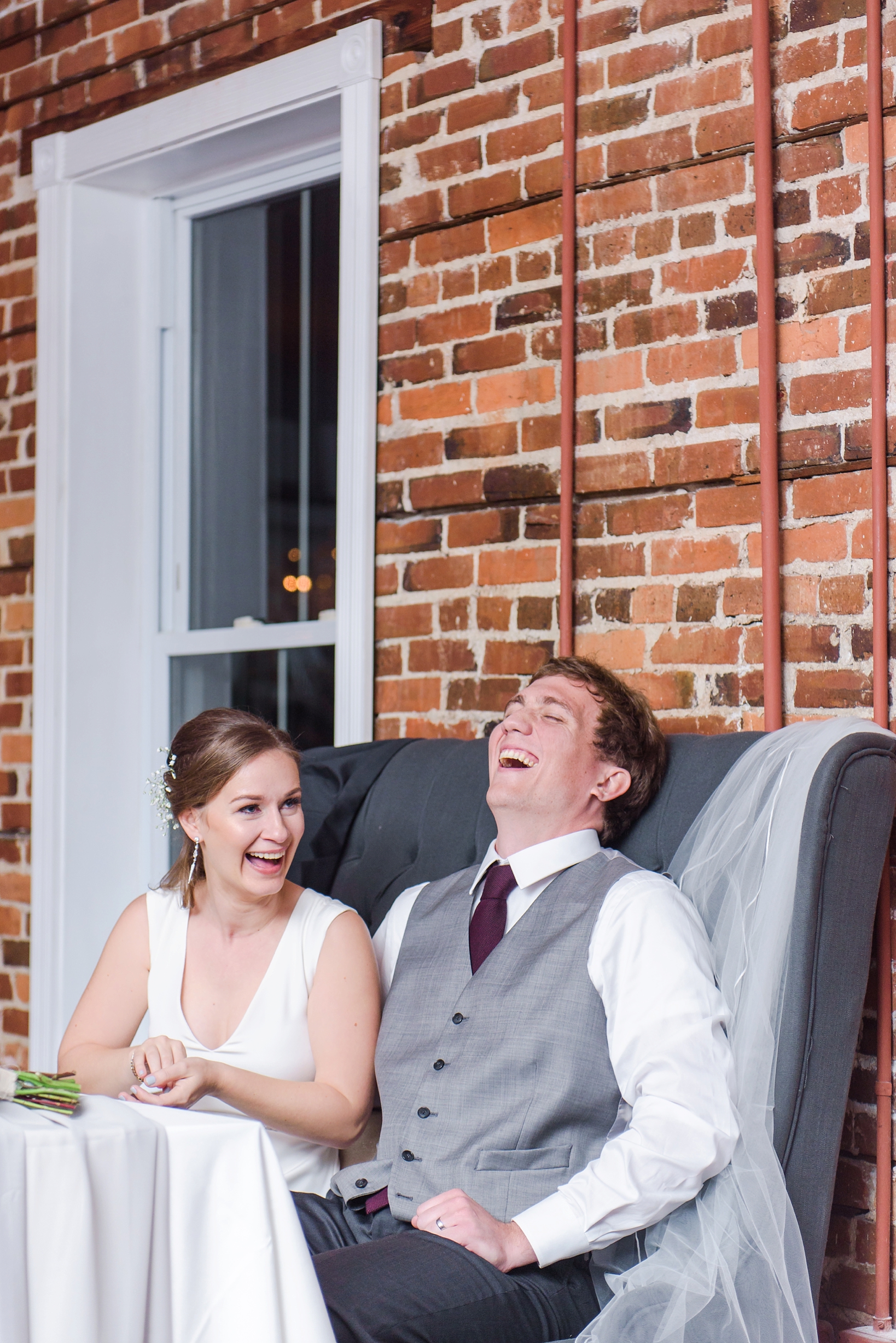 Bride and Groom laugh during the speeches given by the maid of honor and best man