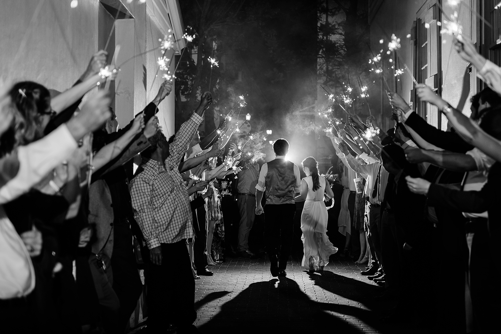 Black and white image of the couple running under the sparklers leaving their reception
