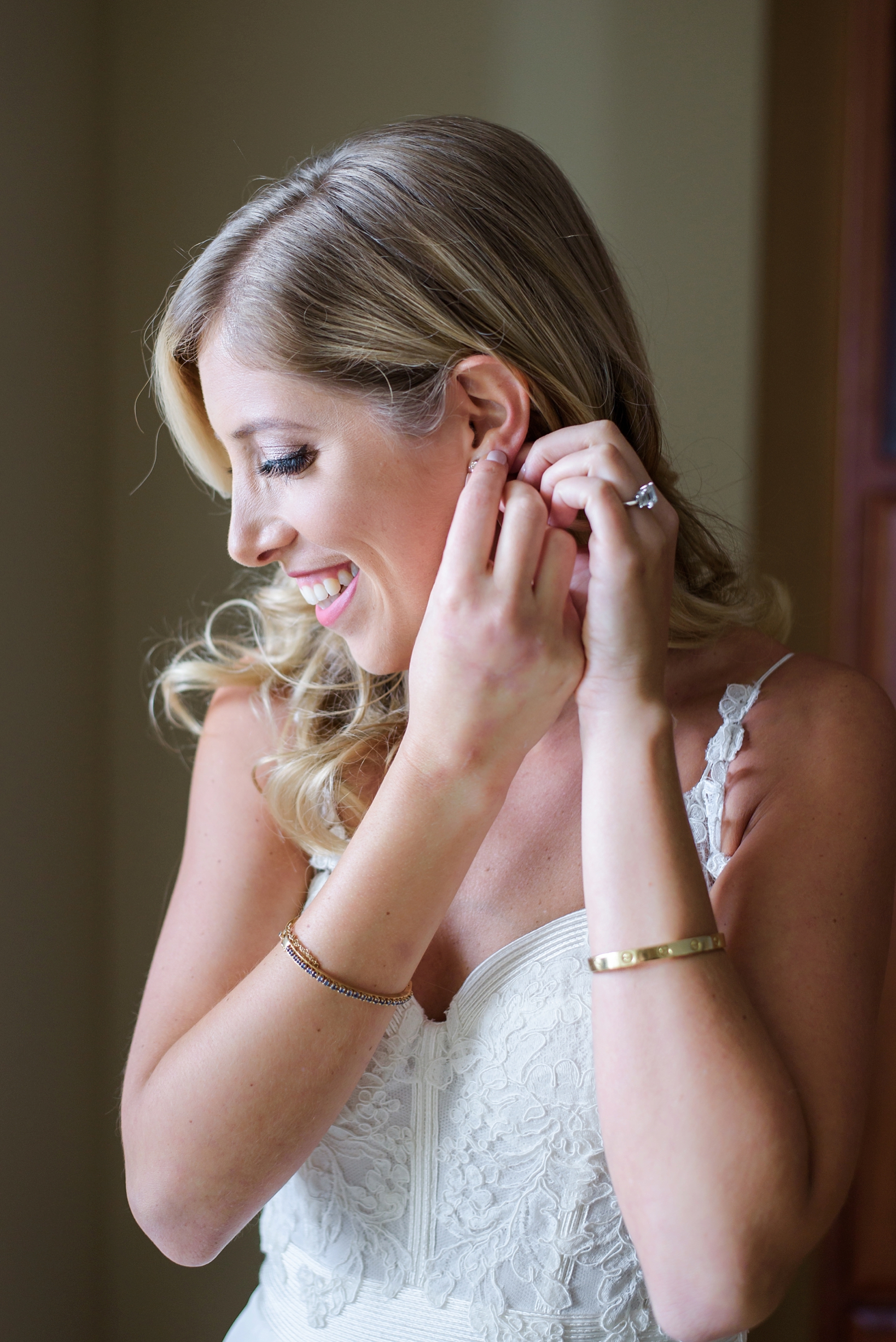 The bride putting her diamond stud earrings in her ears on her wedding day