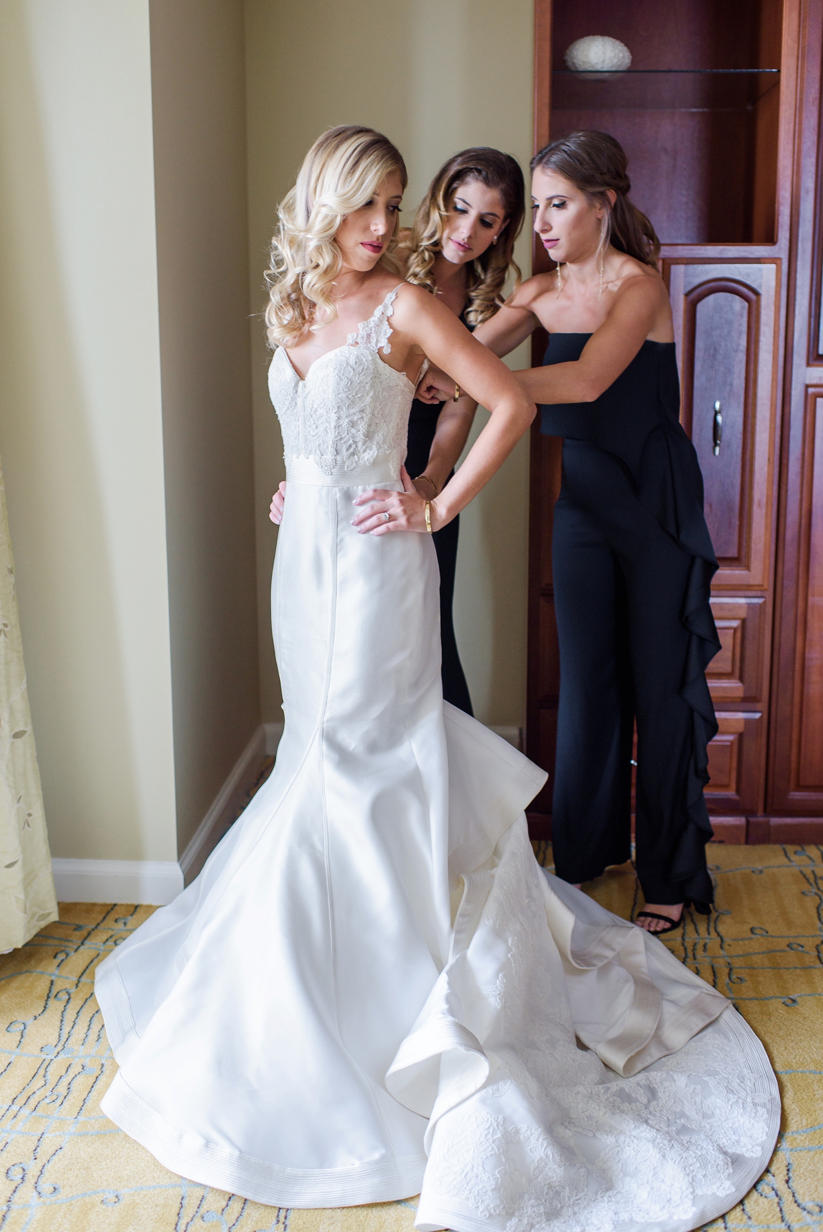 The bride's sisters help her into her wedding dress in Tampa, FL