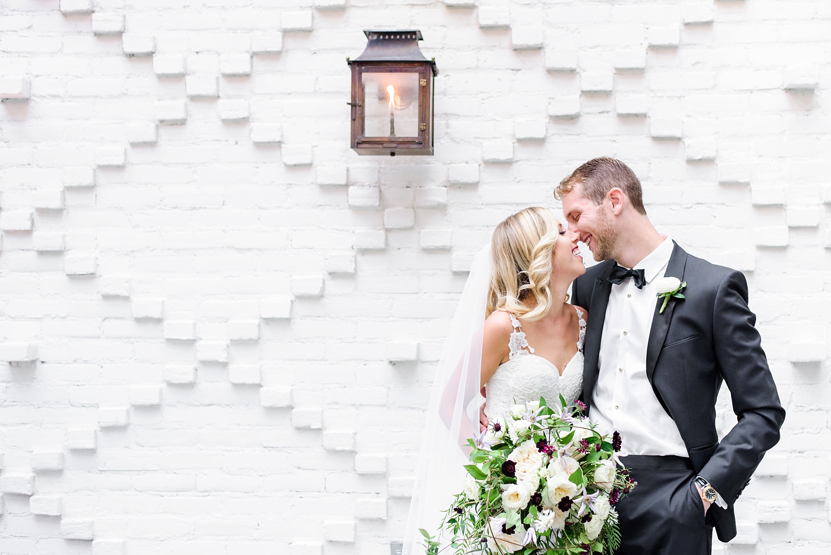 Bride and groom about to kiss in front of a patterned brick wall at the Oxford Exchange in Tampa, FL