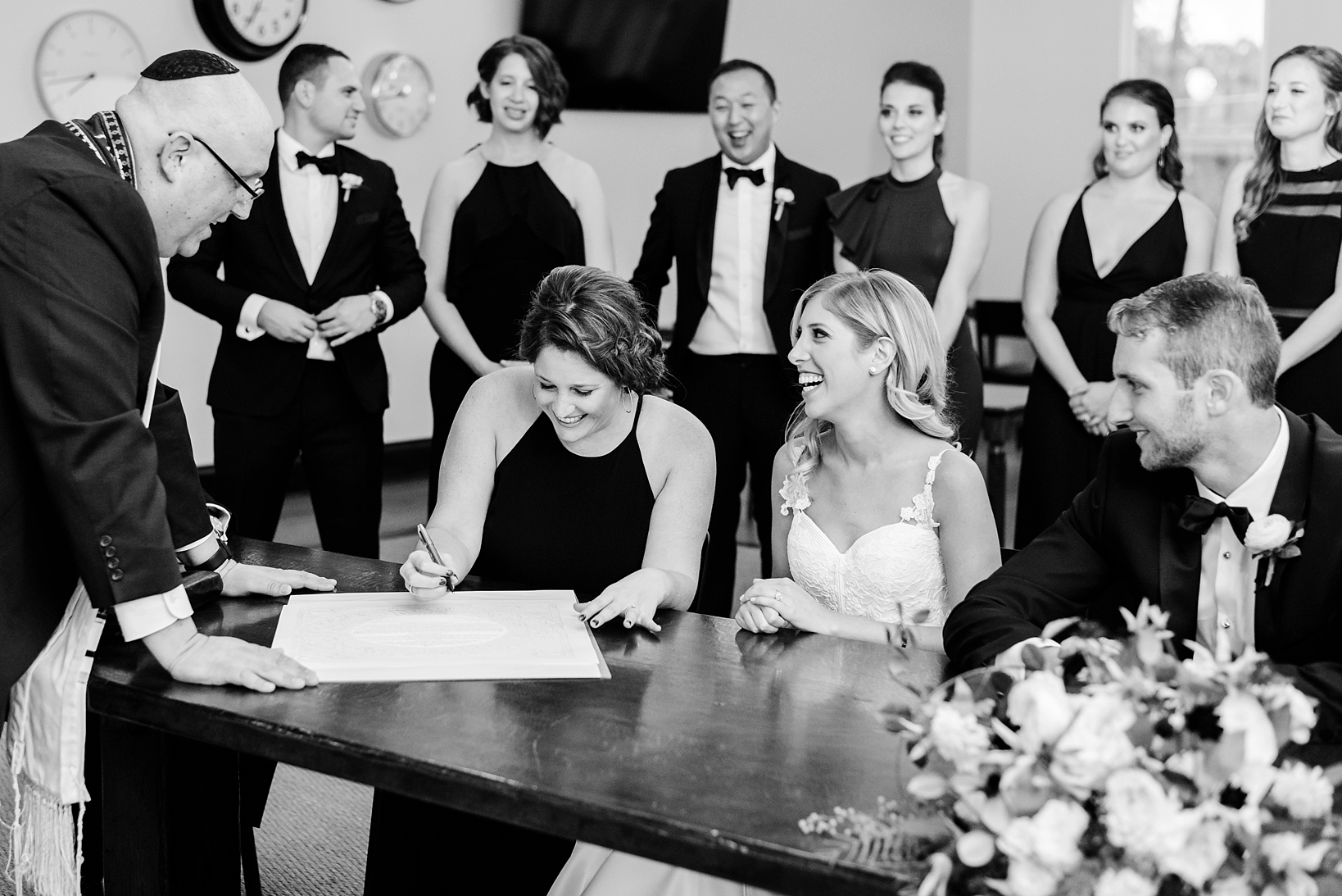 Witnesses sign the Ketubah before the ceremony surrounded by the rest of the Bridal Party