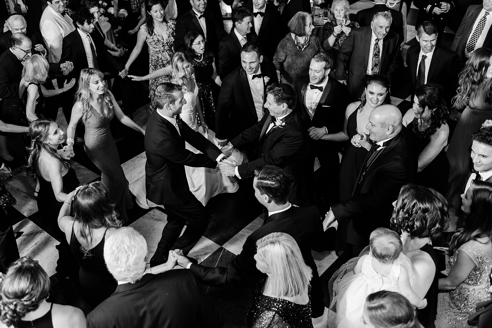 The Groom dances with his Father-in-Law at the center of a circle made by dancing guests during the wedding reception