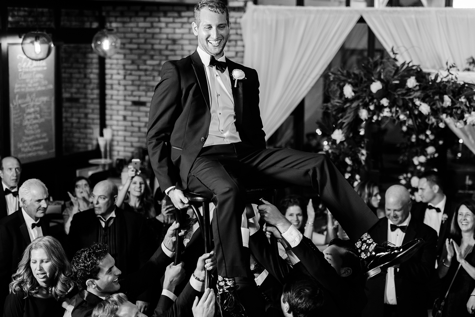 The Groom is lifted up in the air by his groomsmen during the reception celebration by Sarah & Ben Photography