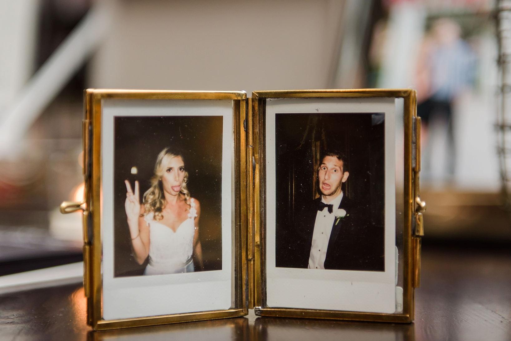 Bride and Groom making silly faces in polaroid pictures being held in a gold frame